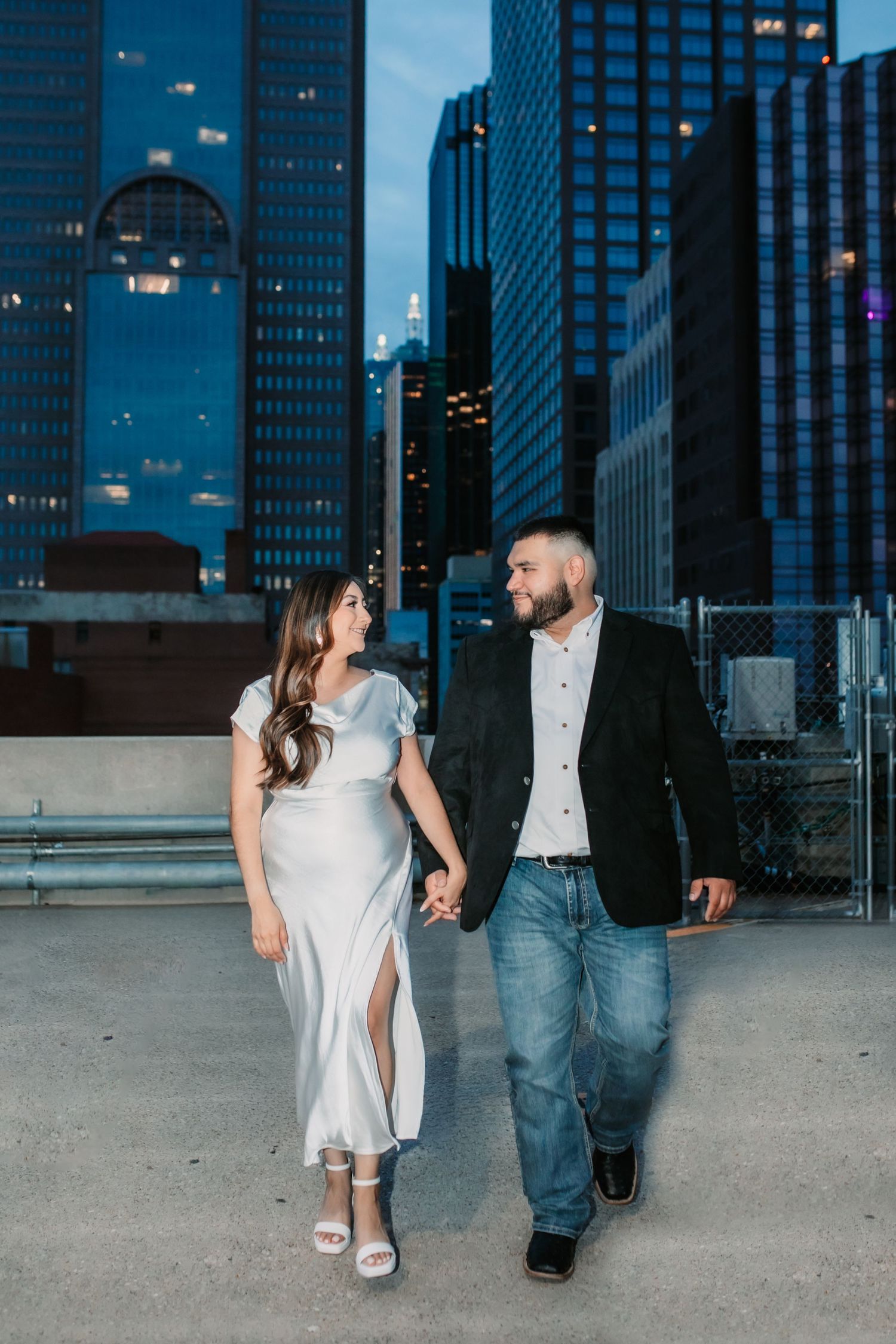 Urban engagement session with city skyline backdrop during blue hour.