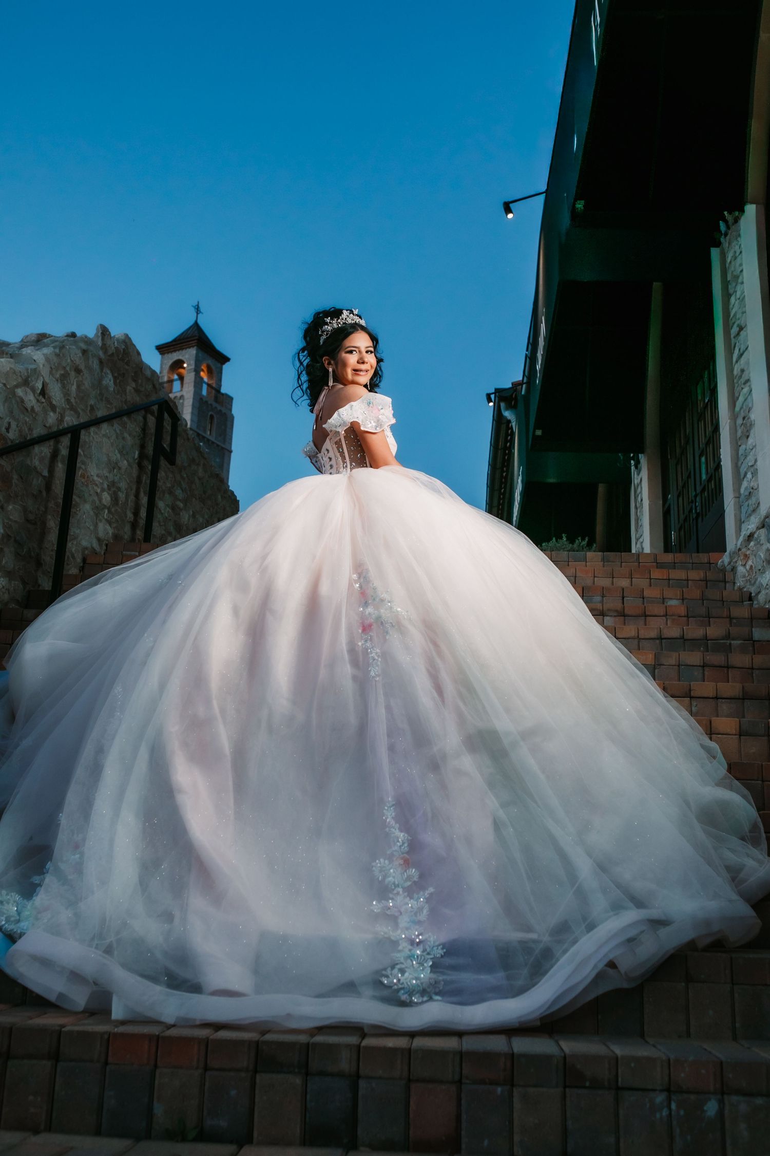 Stunning white ball gown Quinceañera dress photographed against brick wall in dramatic lighting sequence.
