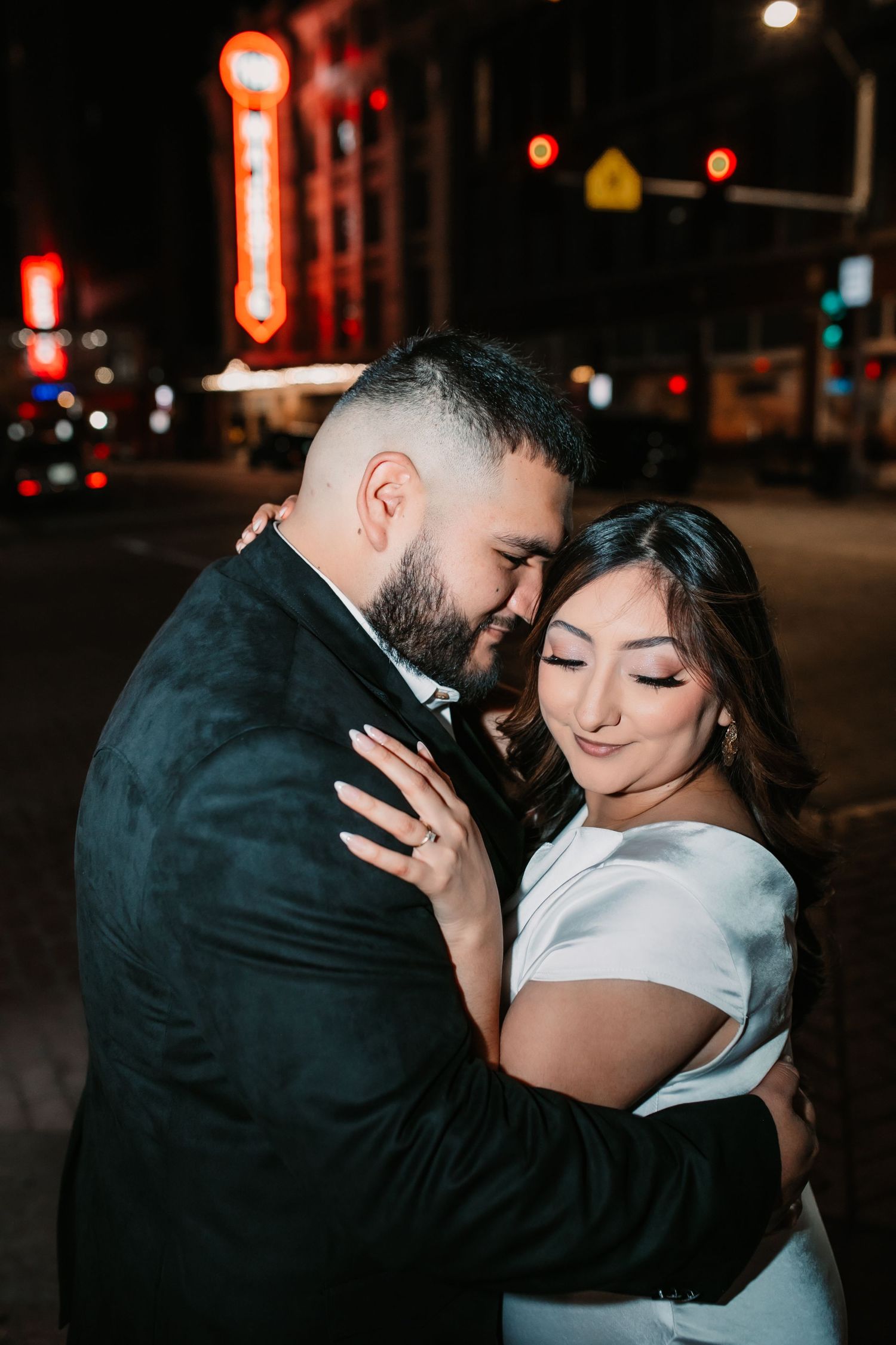 Nighttime urban portrait session with glowing red street lights creating romantic ambiance.