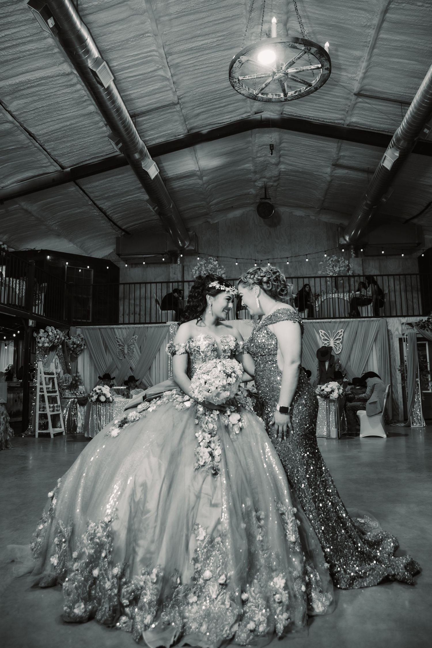 A series of black and white photos showing elegant ballgowns with floral details in what appears to be a rustic venue.