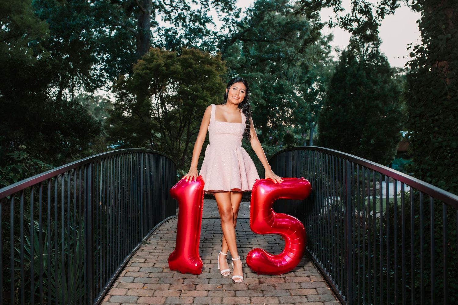A celebratory scene with red number balloons and a pink dress on an outdoor pathway.