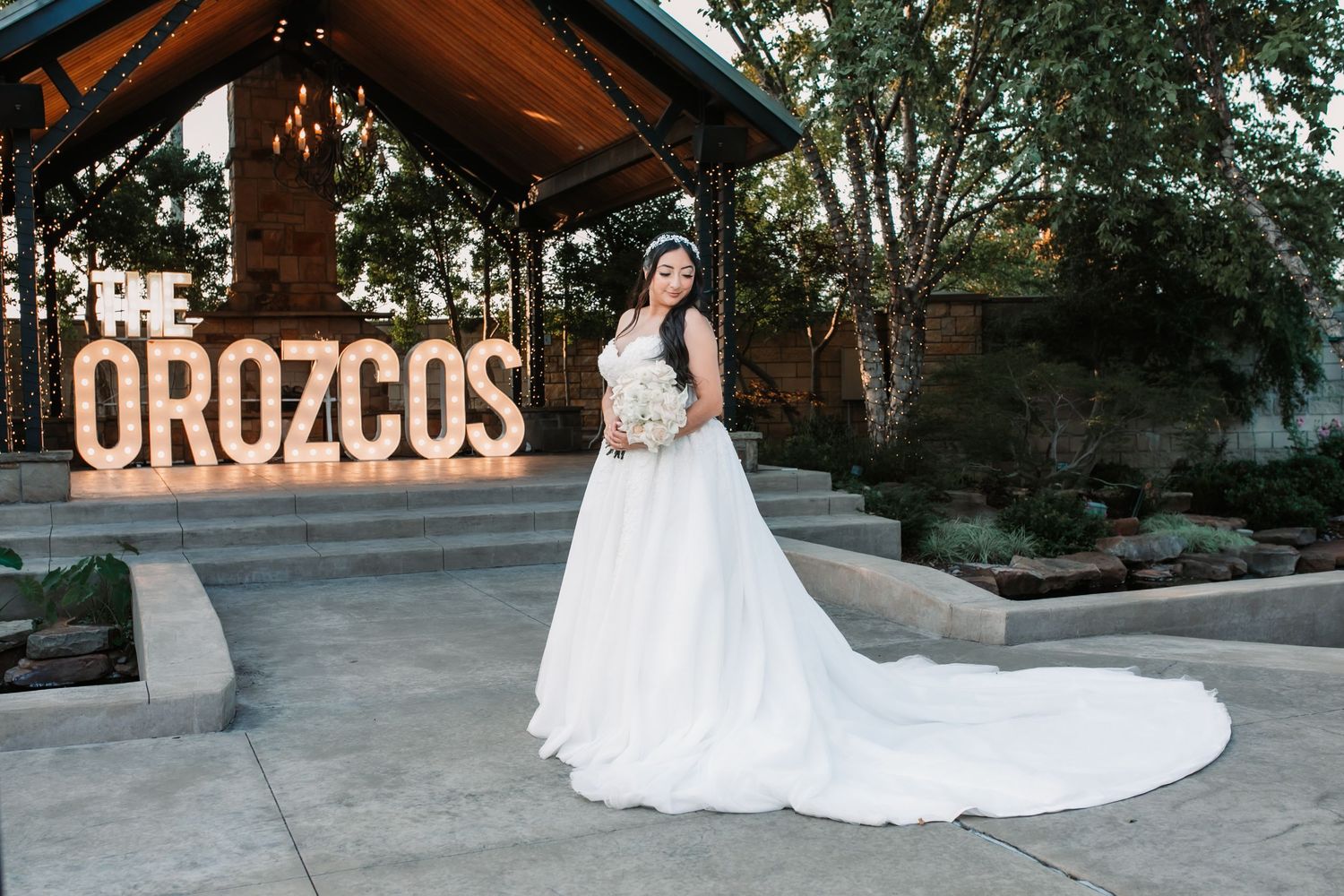 Wedding couple posing in front of illuminated letters outdoors at dusk.