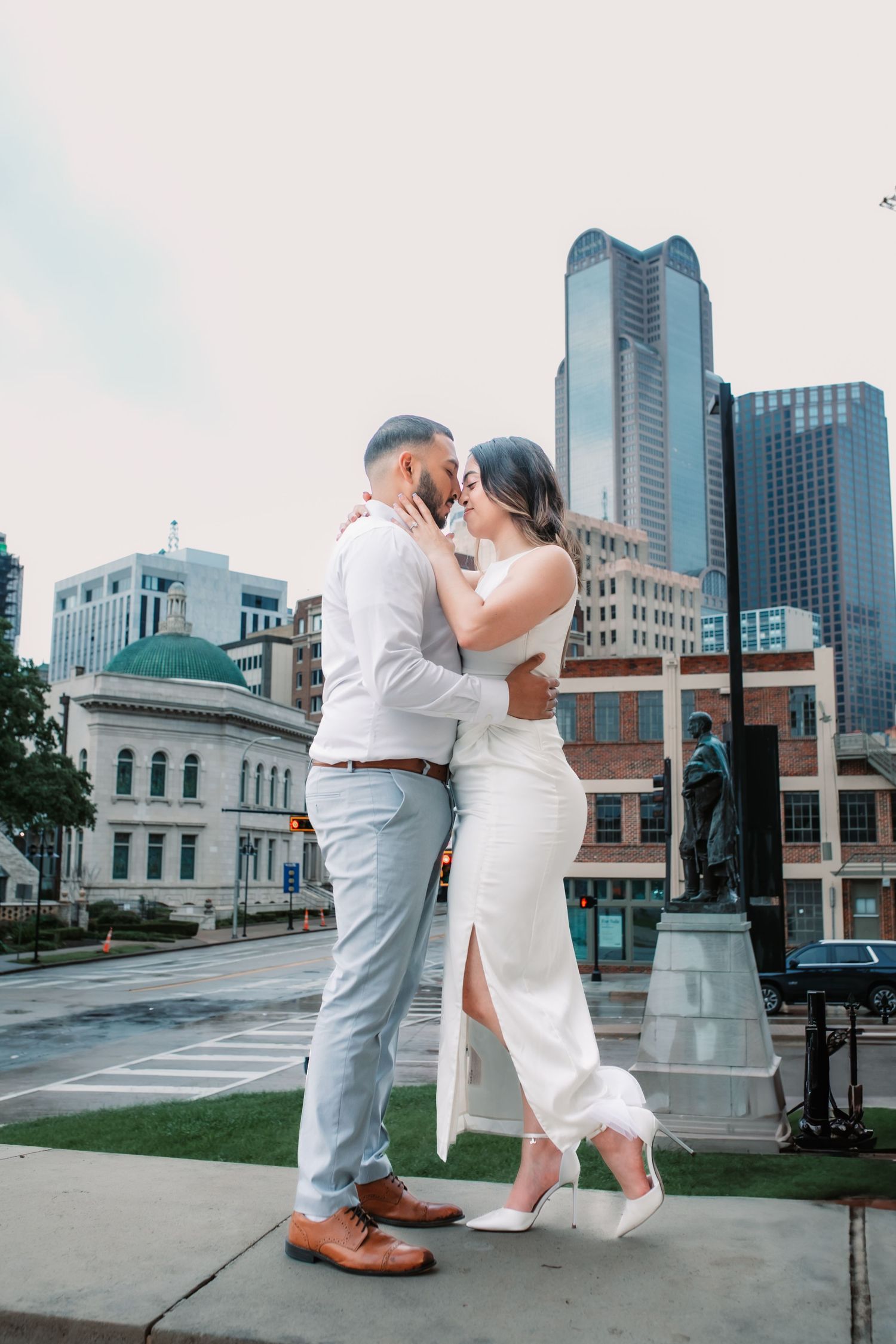 Elegant couple sharing intimate moments on city steps with downtown skyline in background.