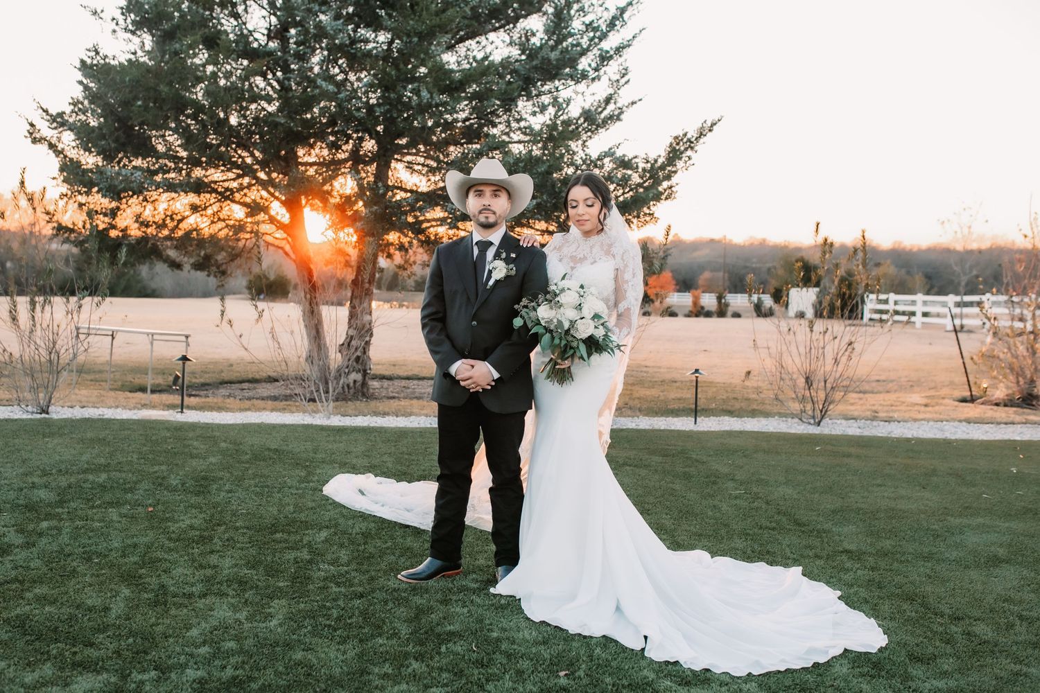 Elegant wedding couple poses in outdoor setting during golden hour.