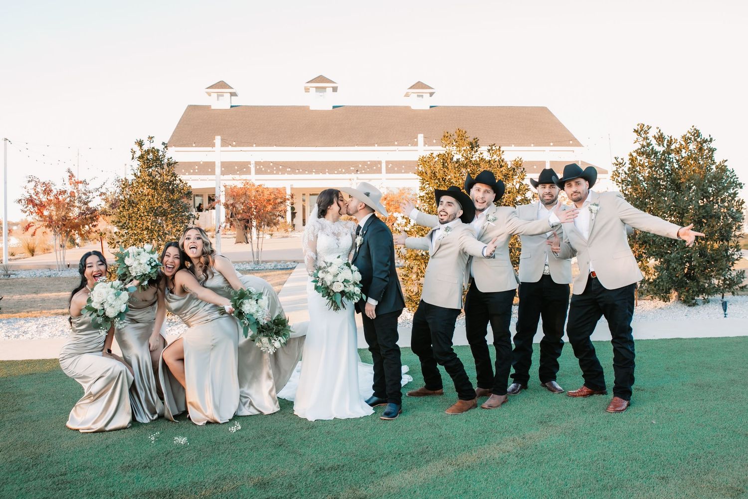 Wedding party posing together on a green lawn during golden hour.