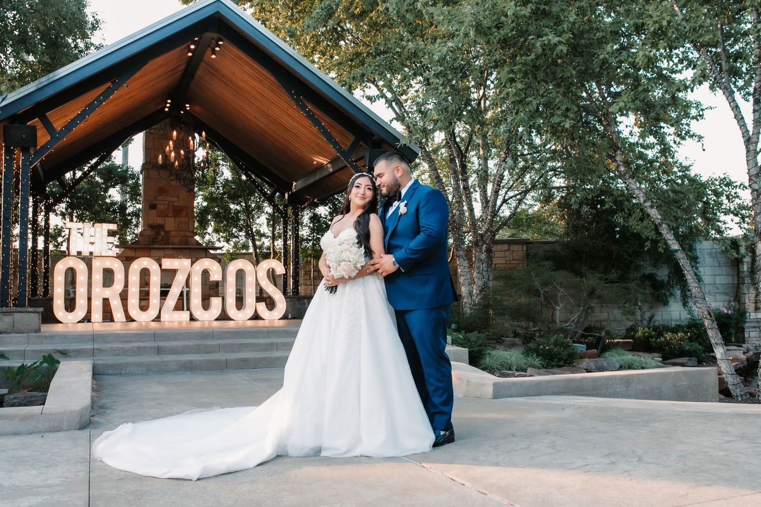 Outdoor wedding photoshoot under trees with rustic wooden structures.