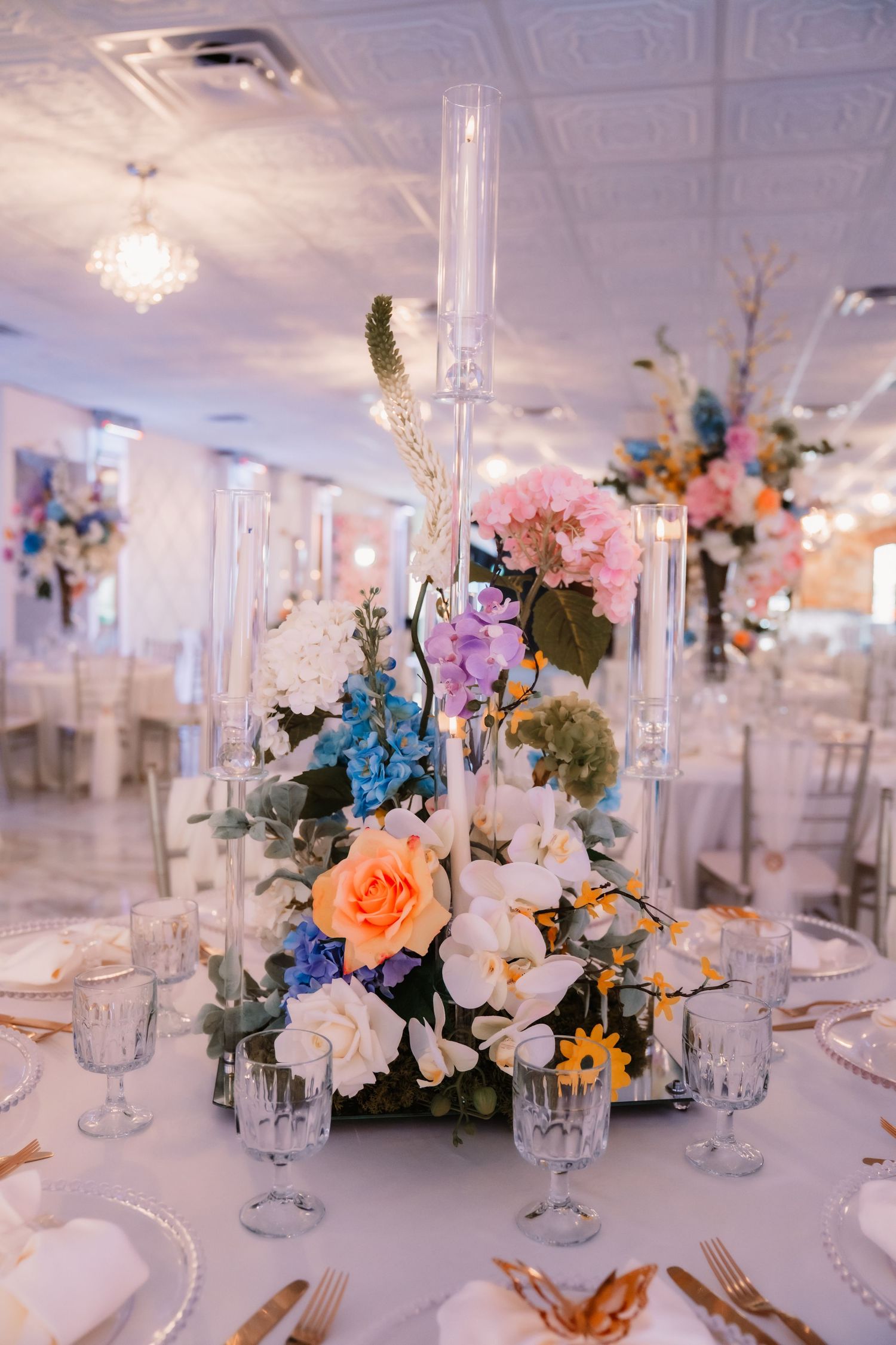 Elegant table settings with crystal glassware and colorful floral centerpieces.
