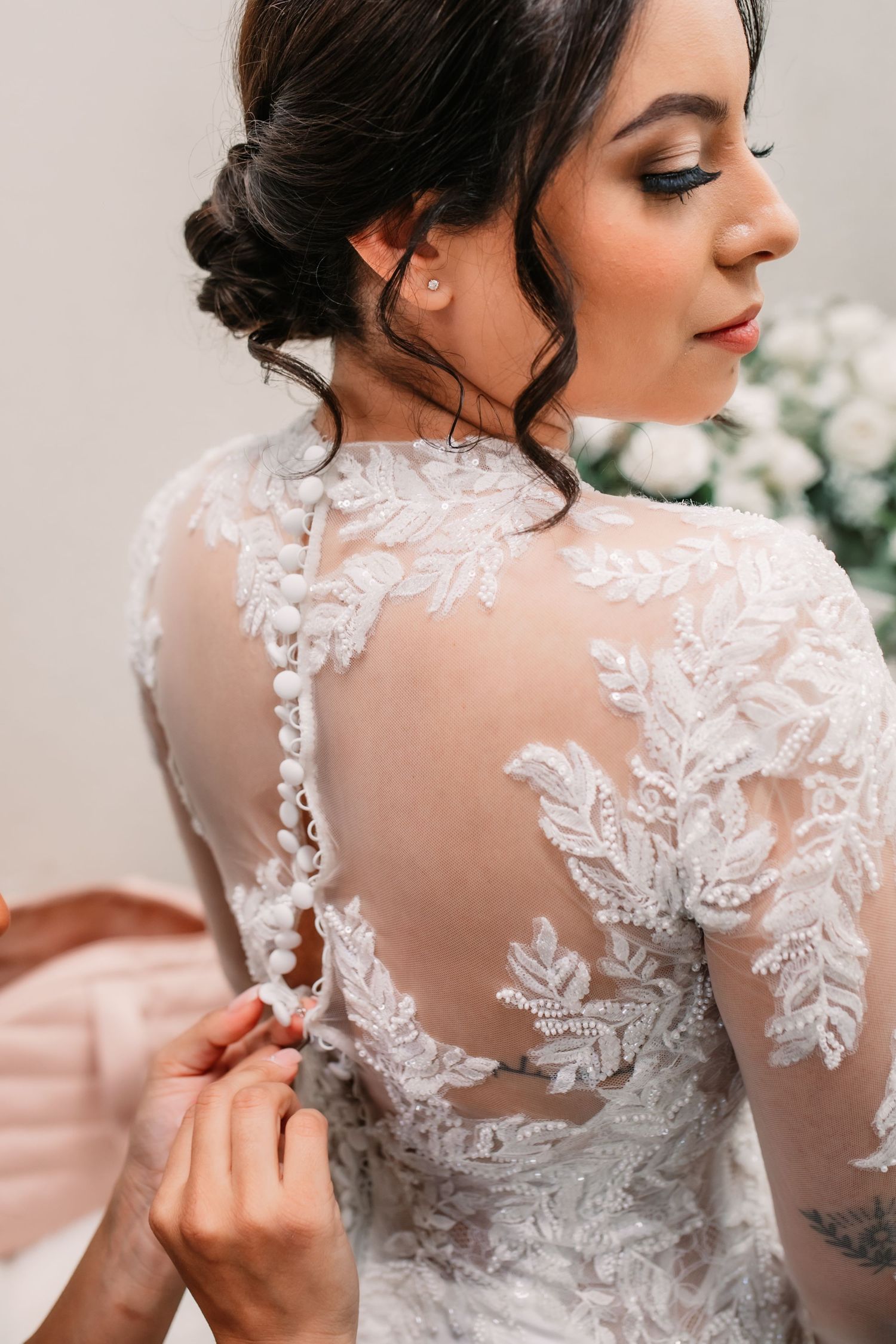 Close-up details of intricate white lace and sheer fabric on a wedding dress back.