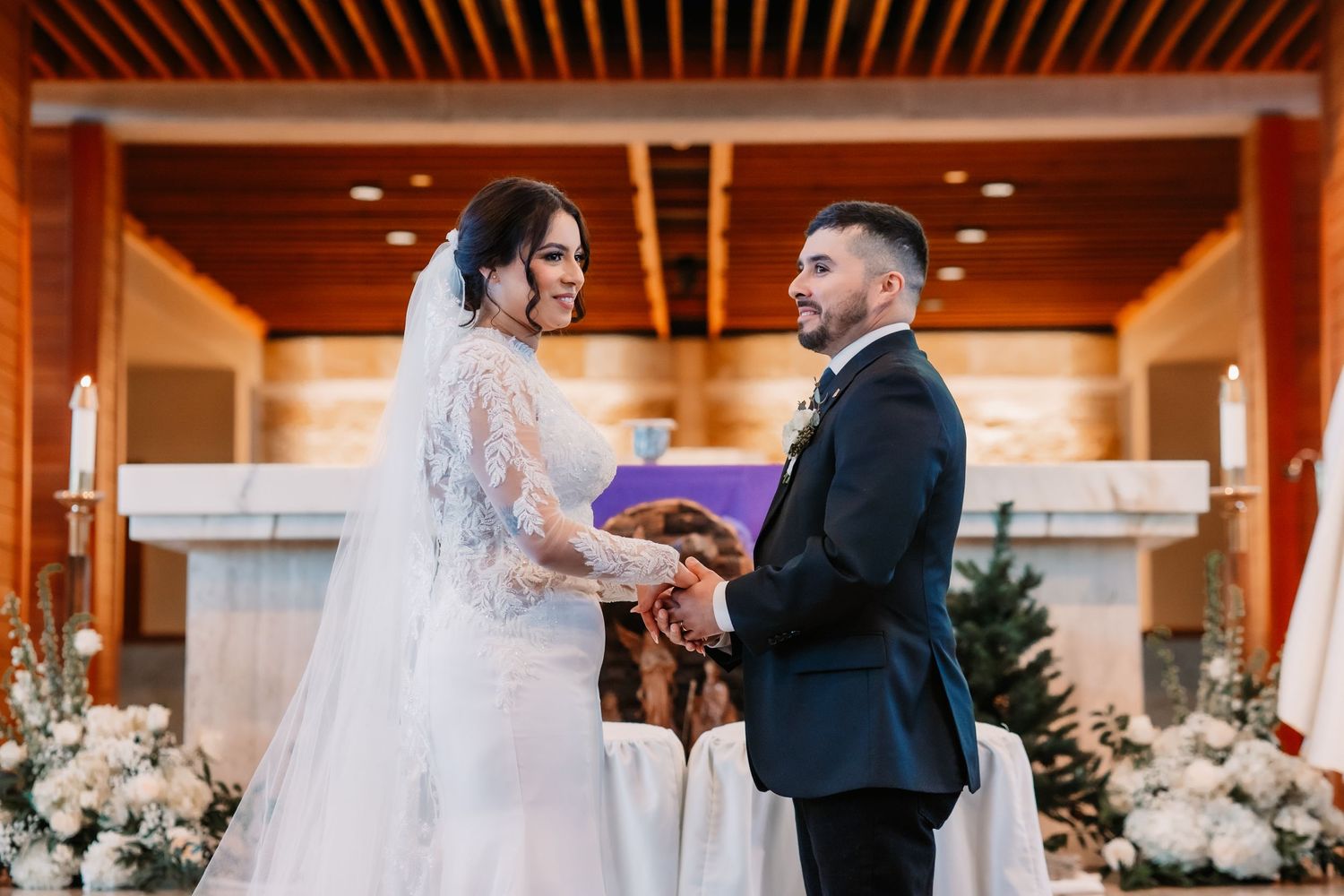 Wedding ceremony in an elegant indoor venue with wooden beams and floral decorations.
