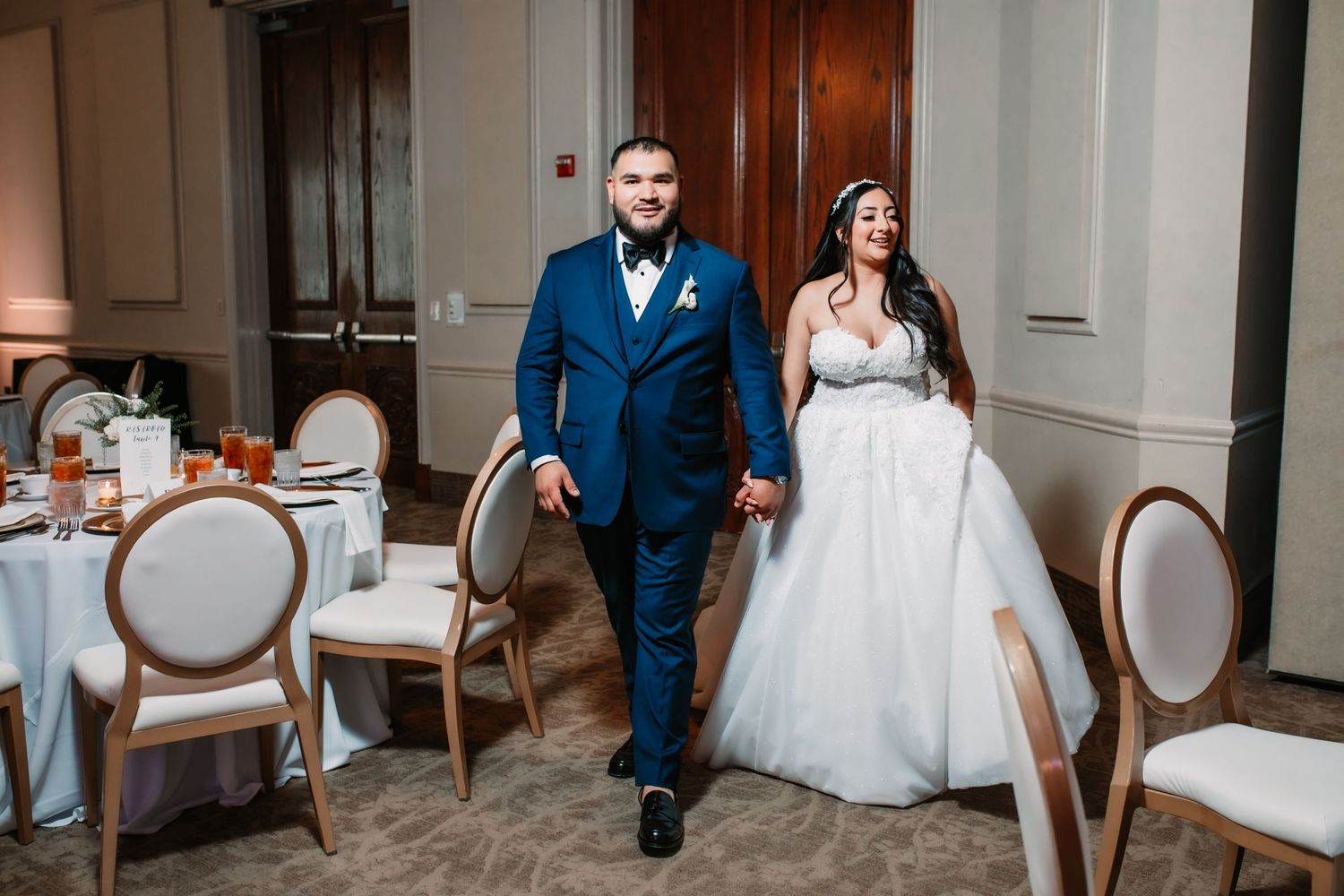 A couple makes their grand entrance into an elegant wedding reception hall.