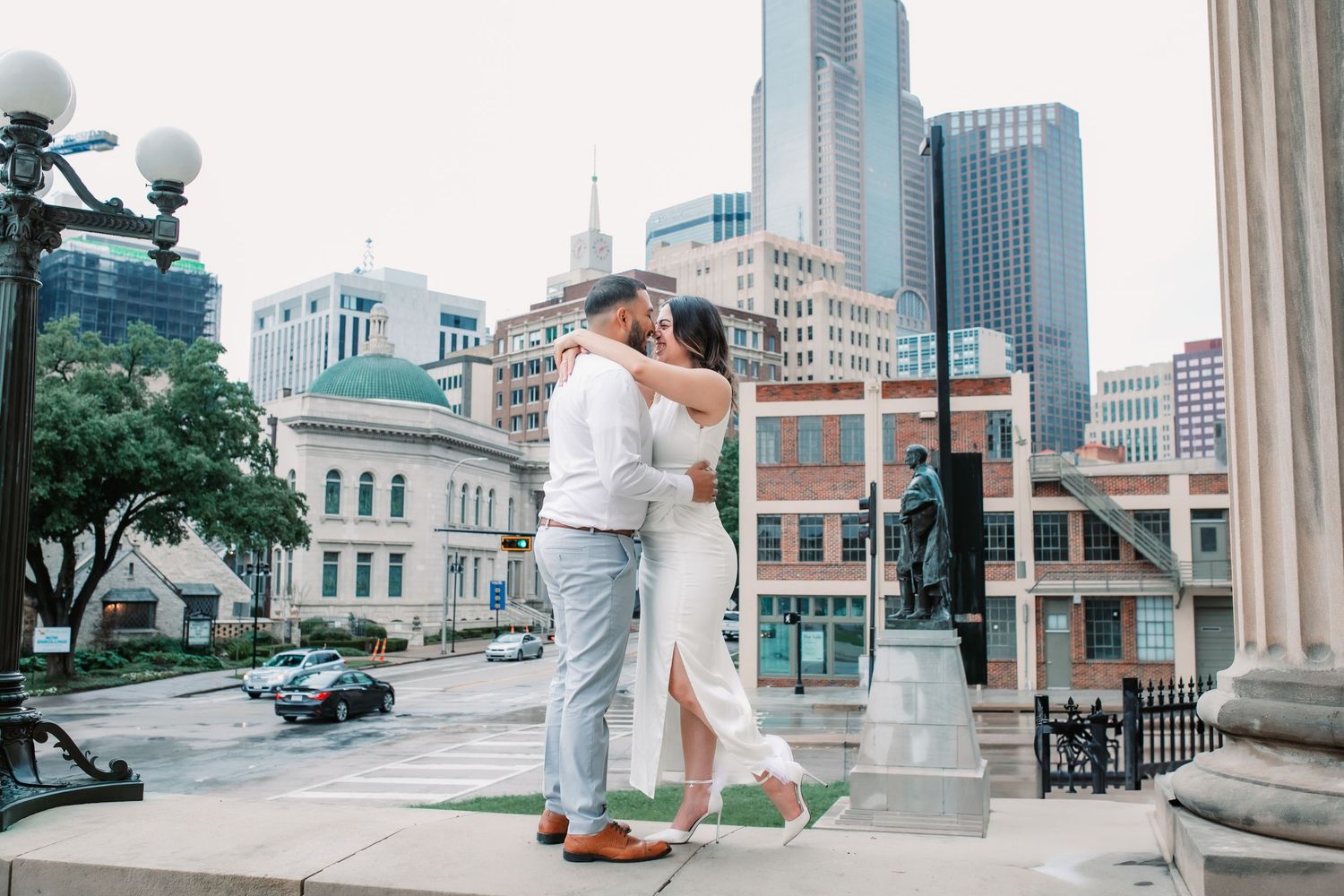 Romantic couple poses against urban cityscape backdrop with classic architecture and modern buildings.