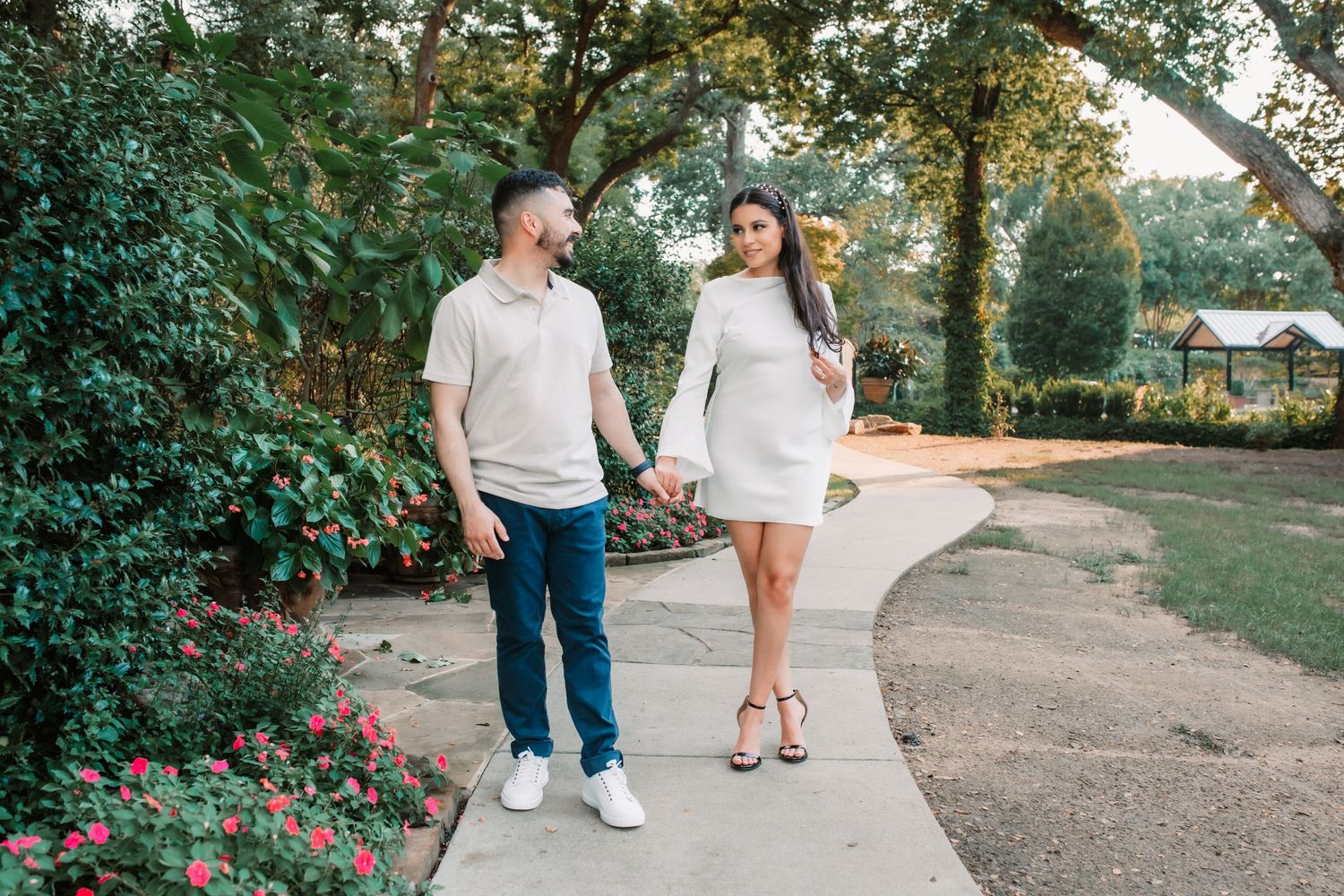 Casual engagement session with couple walking along garden pathway.