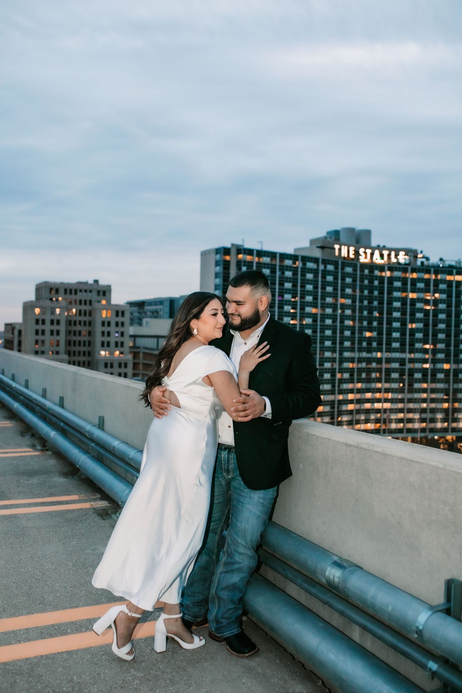Rooftop engagement photos with downtown buildings and evening sky in the background.