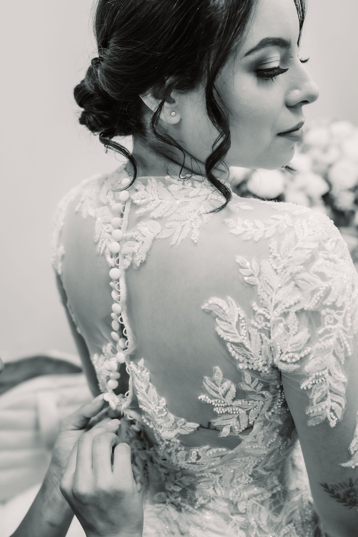 Black and white bridal portrait showcasing intricate lace details on the back of a wedding dress.