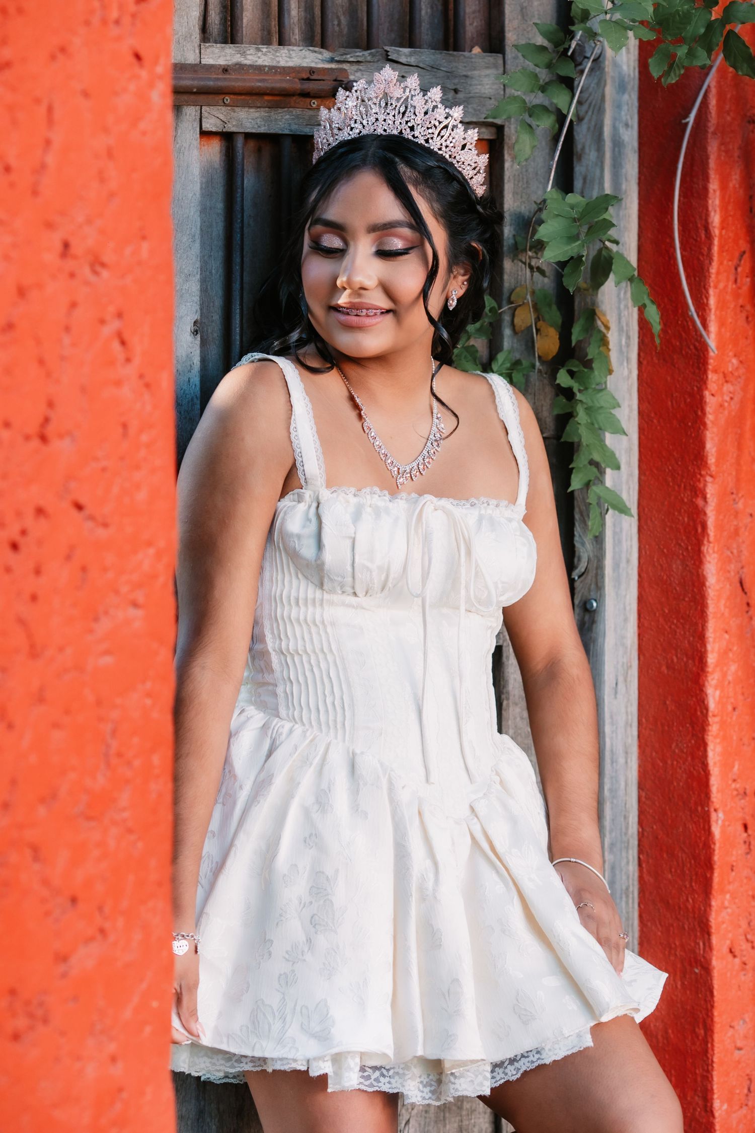 White dress against vibrant orange wall with greenery and decorative elements.