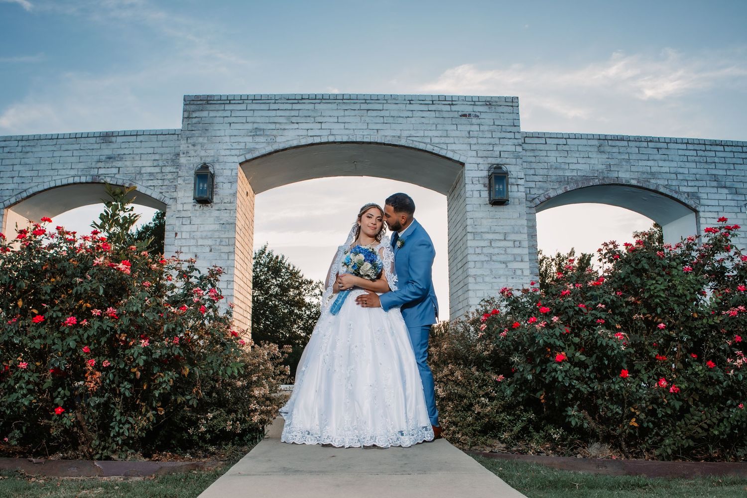 Wedding photography session at a venue with red roses and white architectural features.