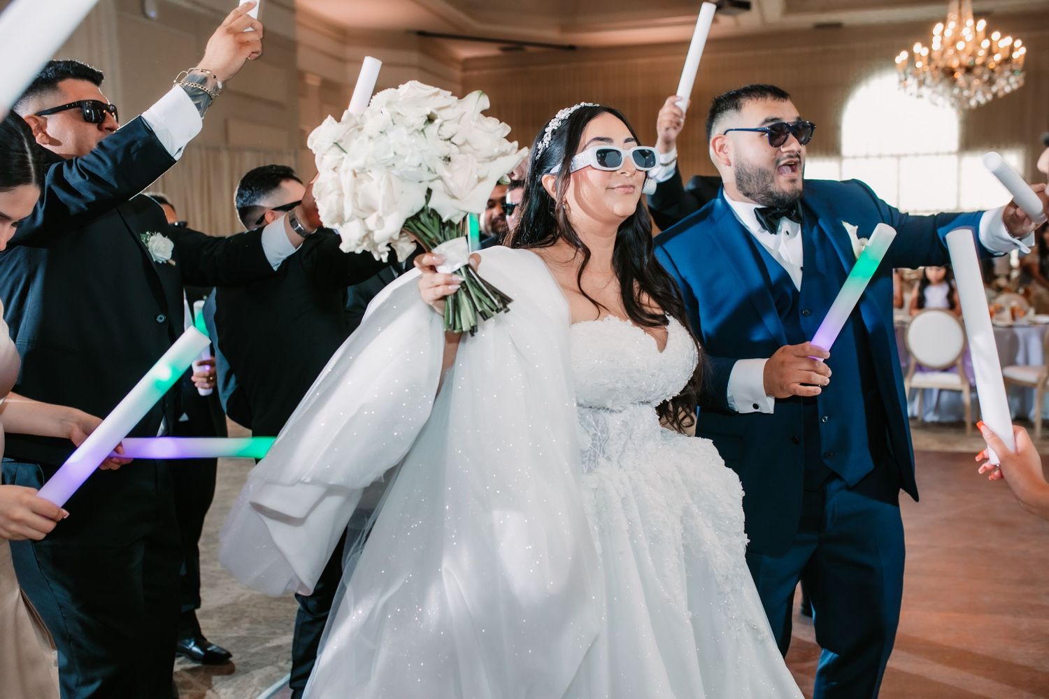 Wedding couple sharing a dance surrounded by guests in an elegant indoor venue.