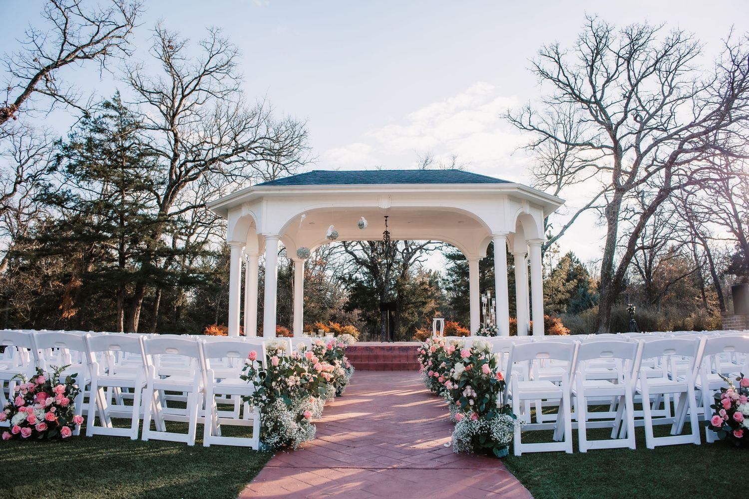A series of outdoor wedding ceremony setups with white gazebos and chairs arranged in rows on brick pathways.