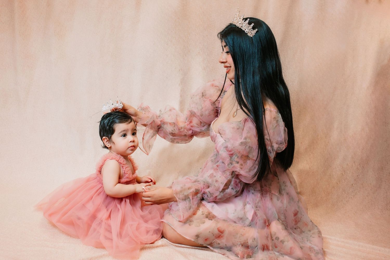 A series of soft, dreamy portraits in pink and peach tones showing intimate family moments against a neutral backdrop.