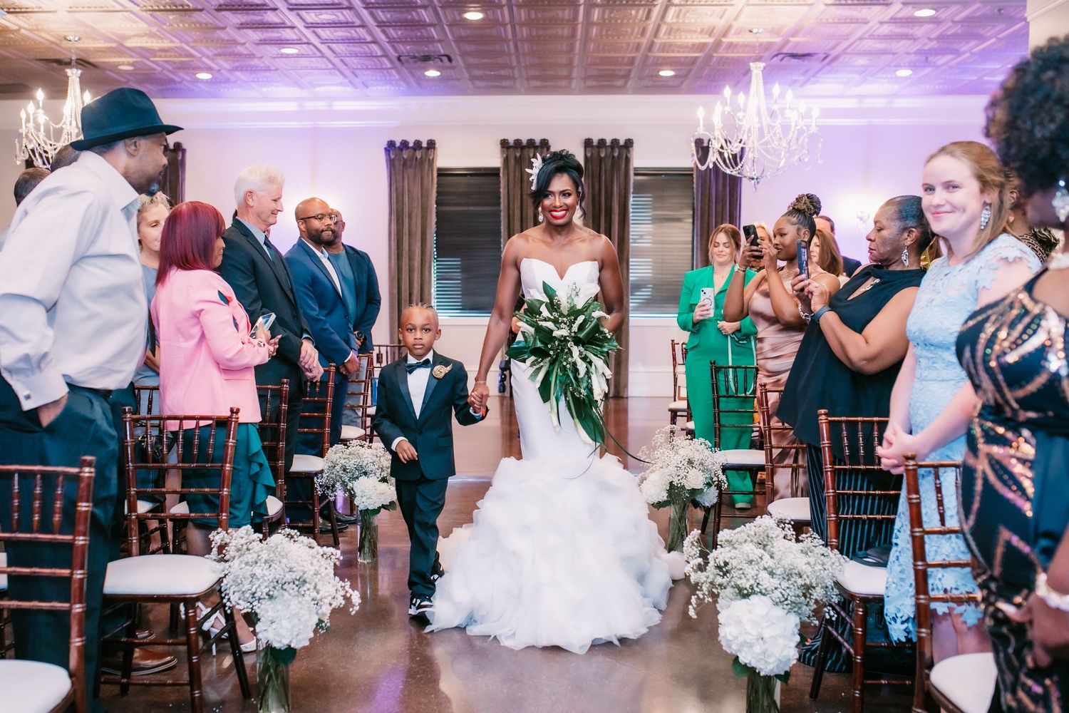 Wedding reception celebration with guests dancing under purple lighting.
