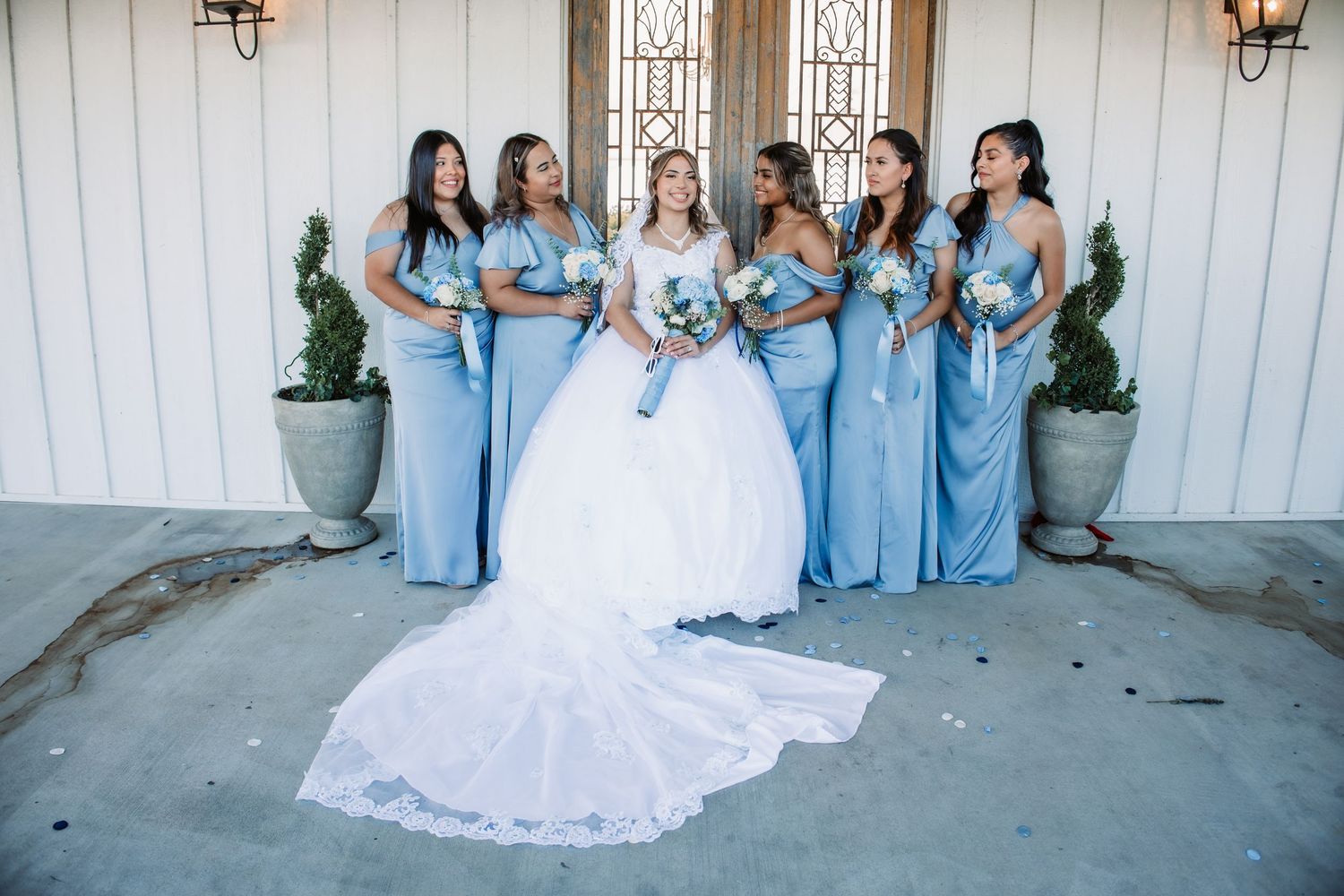 Wedding party in coordinated blue and white attire posed together outdoors.