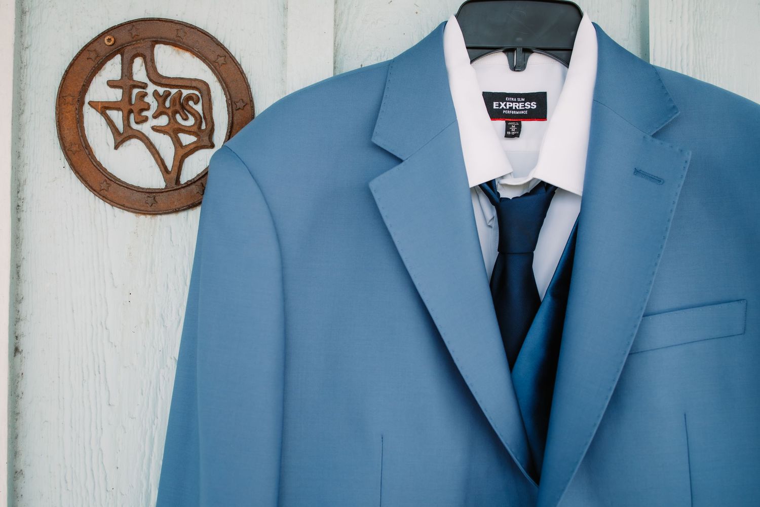 Row of blue groomsmen suits hanging on display before wedding ceremony.