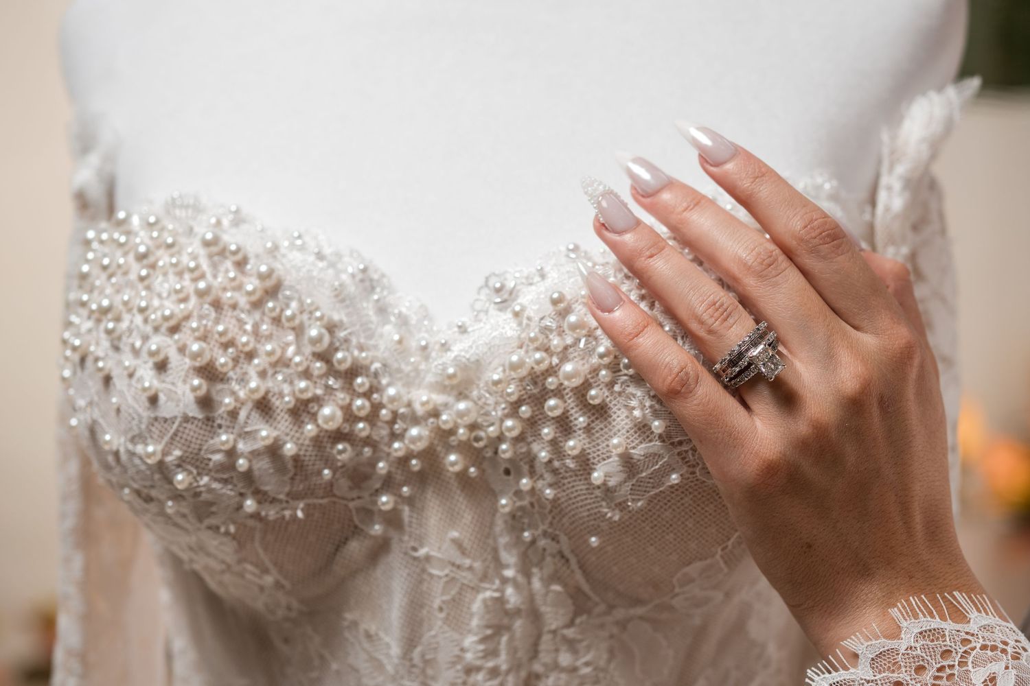Close-up of bride wearing her wedding ring and detailed bridal gown