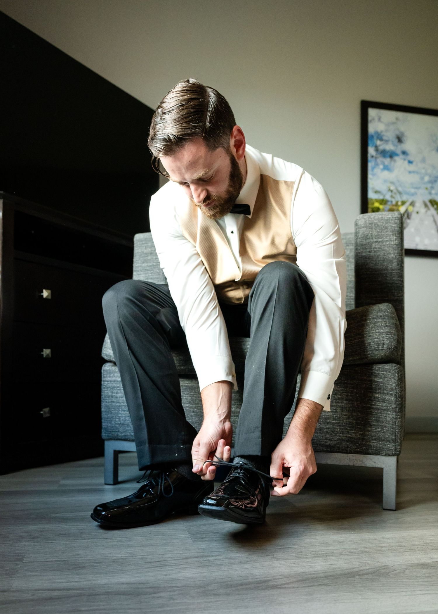 Groom putting on his shoes while getting ready for the wedding