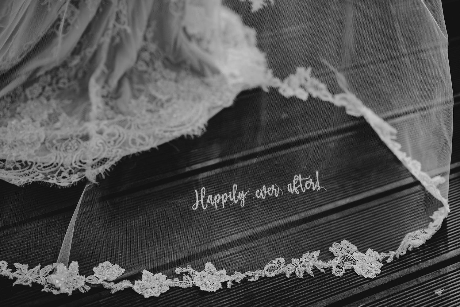 Black and white close-up of bridal veil with lace trim and Happily Ever After inscription.