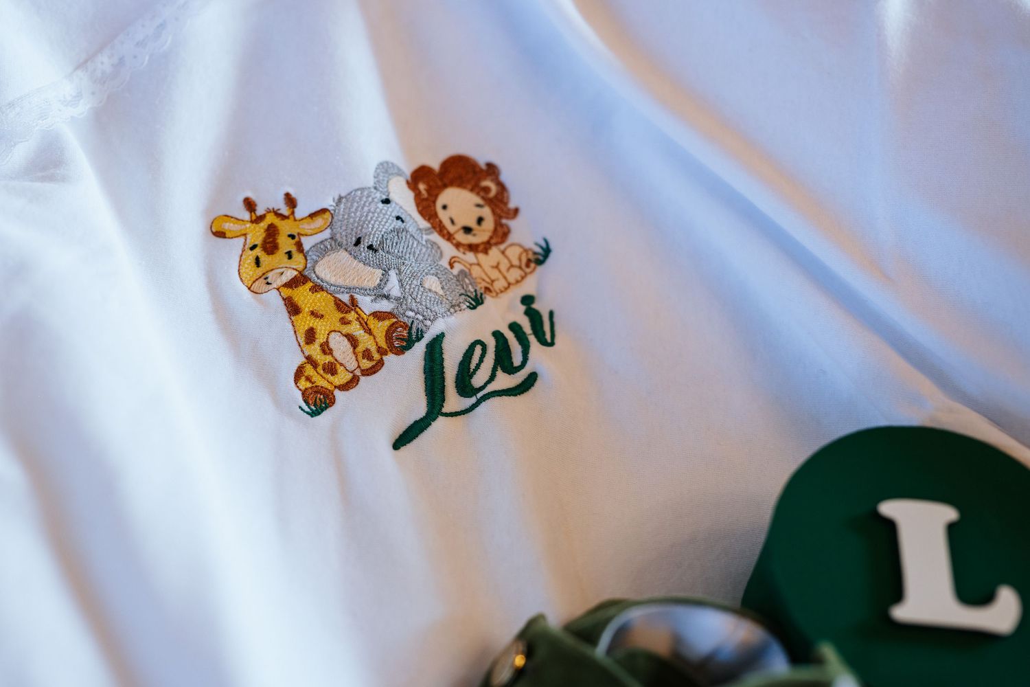 White children's shirt with embroidered jungle animals and personalized name Levi, perfect custom baby gift.