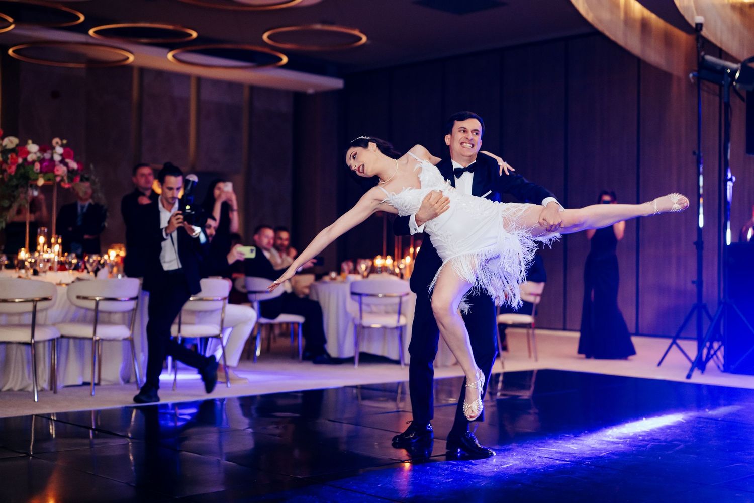Elegant ballet dancers perform a stunning lift at a wedding reception with candlelit tables in the background.