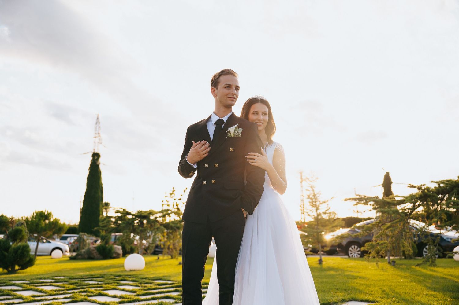 Bride and groom posing together in lush garden during golden hour at outdoor wedding.