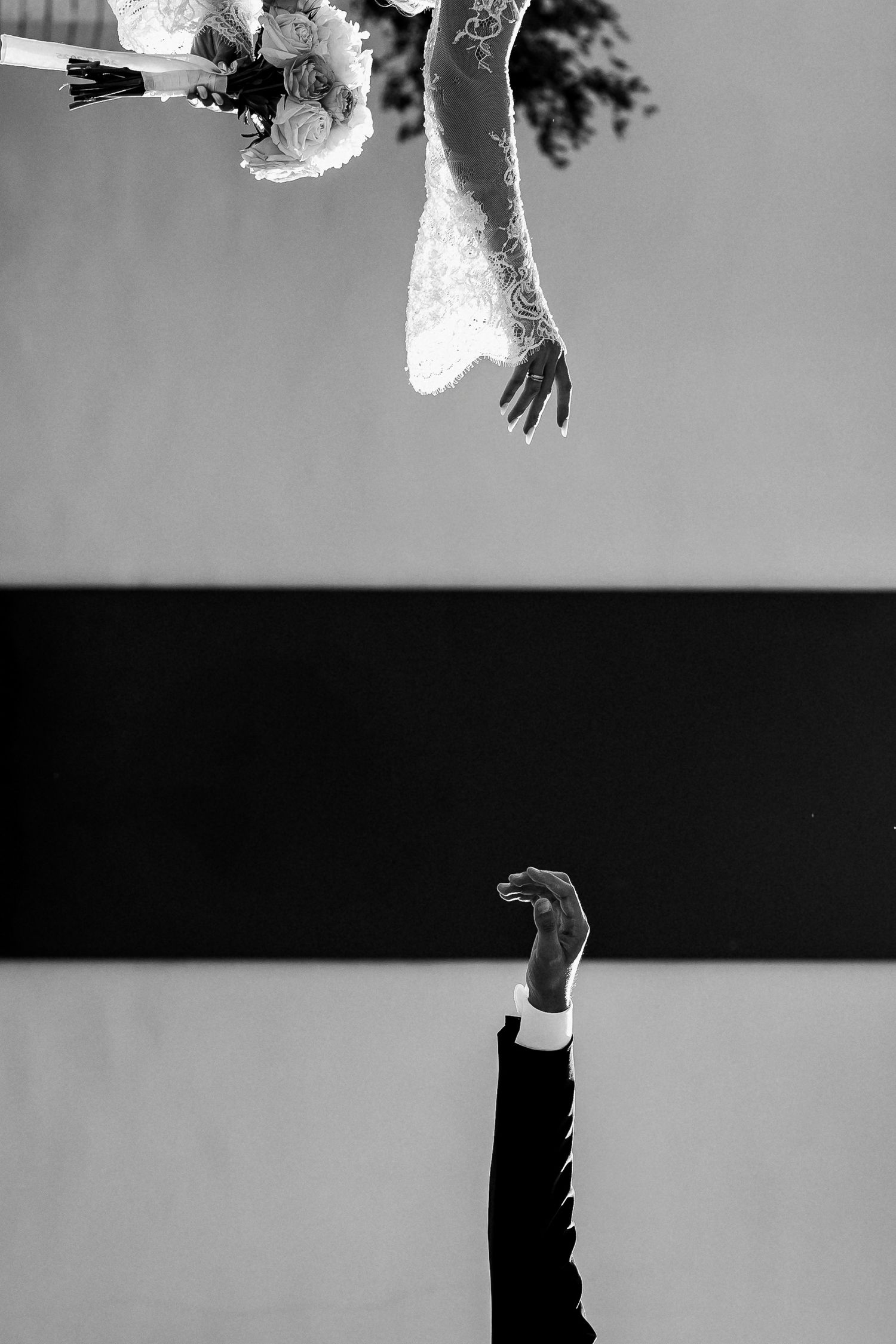 Artistic black and white split image of bride and groom reaching toward each other.