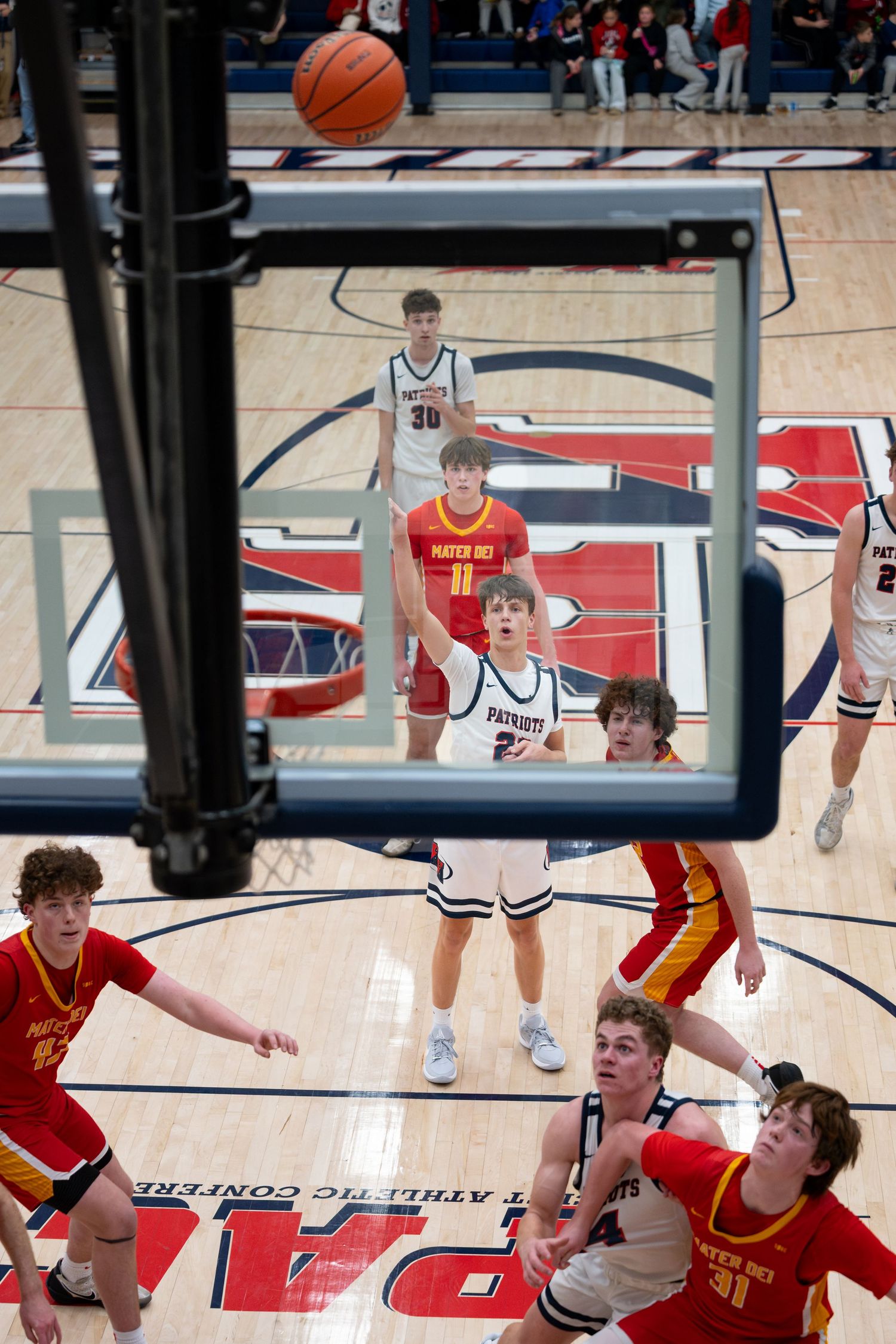 Heritage Hills Patriots Boys basketball game viewed through the hoop as a player shoots during an intense high school Patriots game.