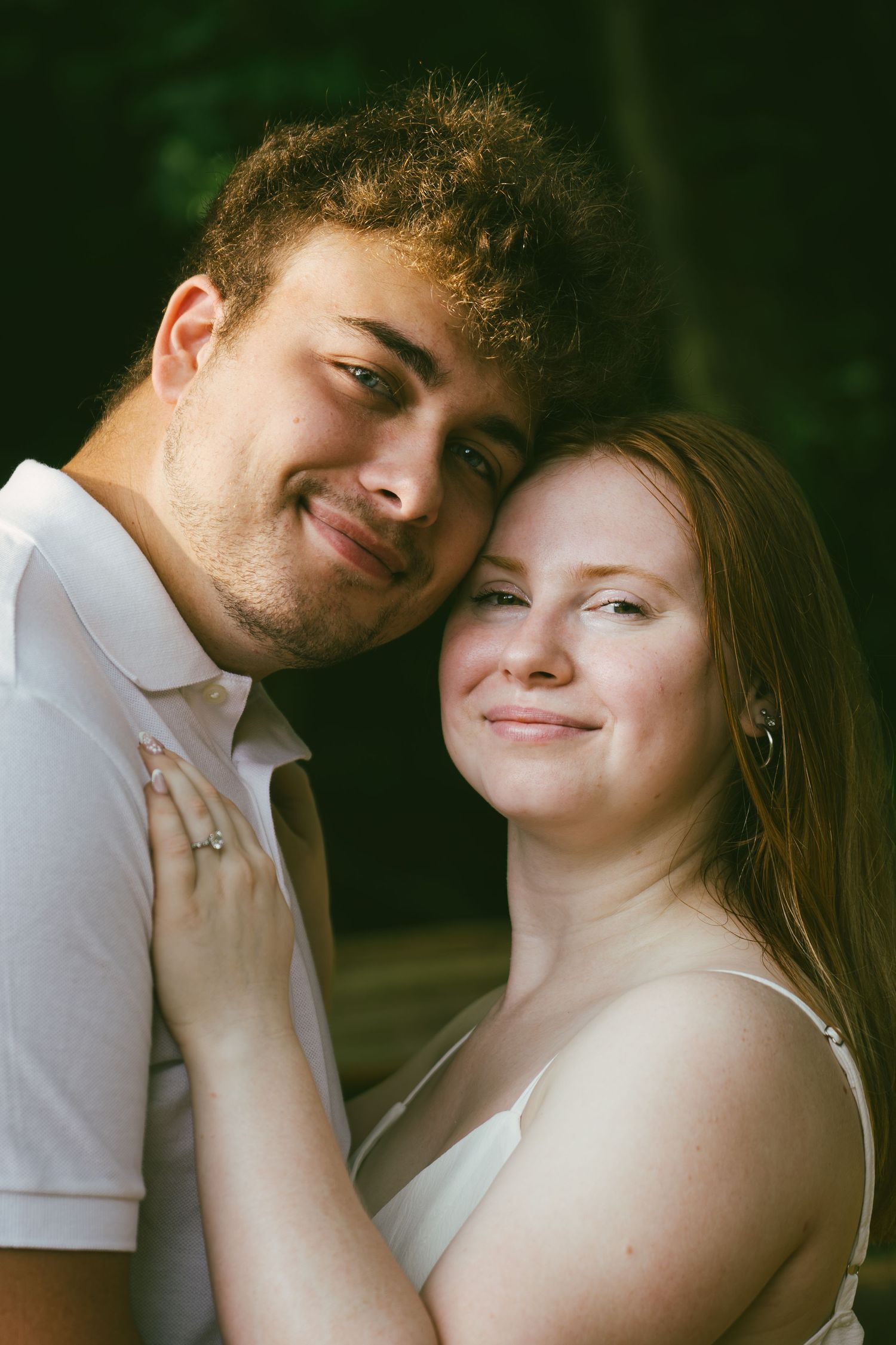 Young couple sharing a tender moment outdoors, smiling closely together.