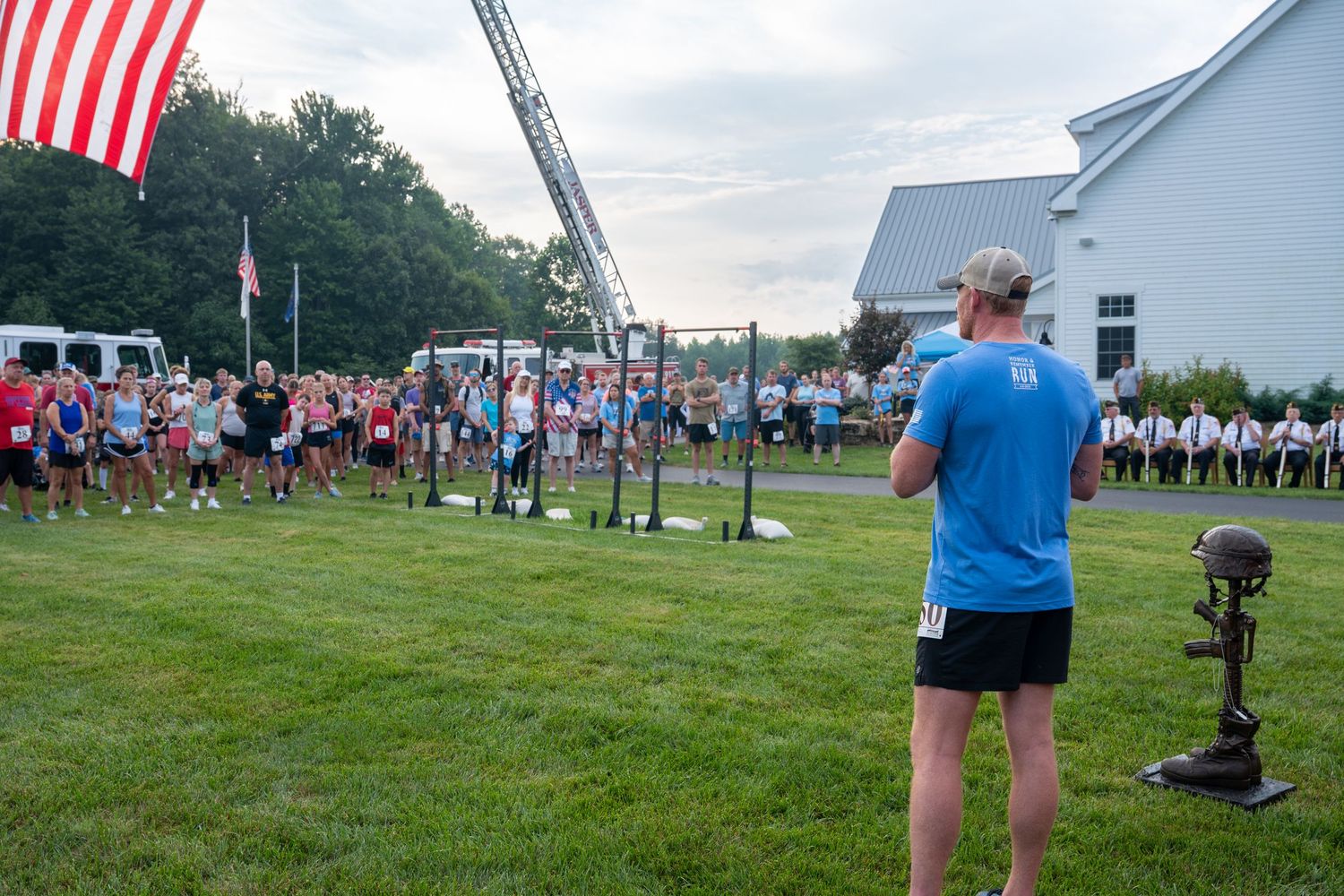 Participants gathered on a lawn before 2026 Honor and Remember Run at Cool Springs, OFS Brands with American flag and fire truck.