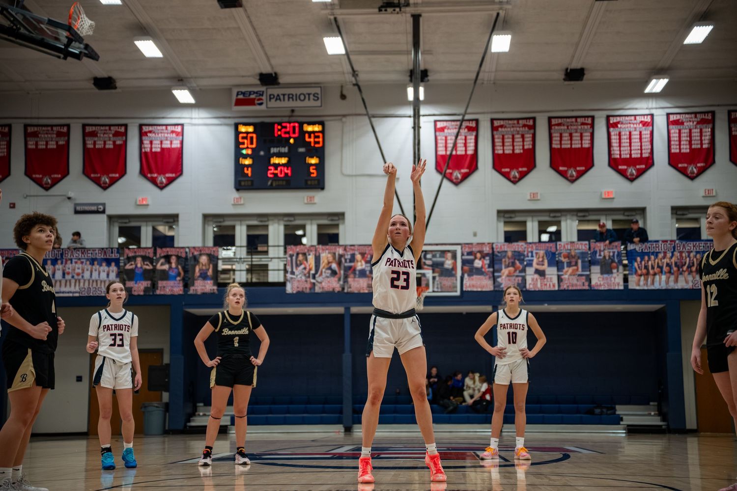 Heritage Hills Lady Patriots Female basketball player number 23 shoots a free throw in a high school gymnasium during a game.