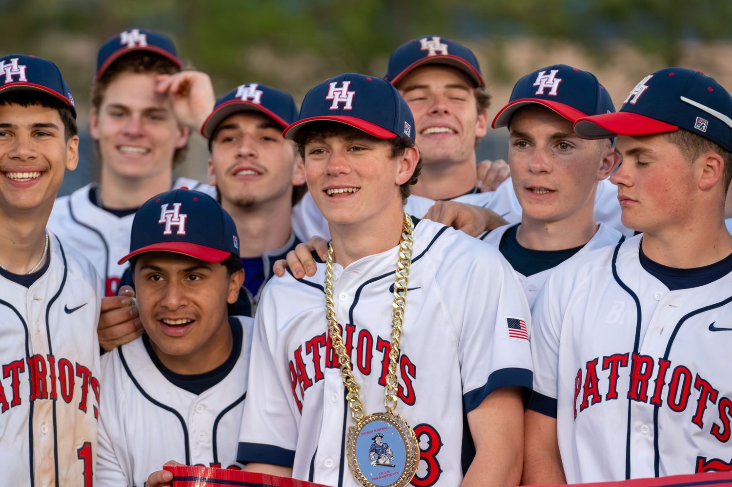Heritage Hills Patriots baseball team poses together smiling with a championship medal after winning.