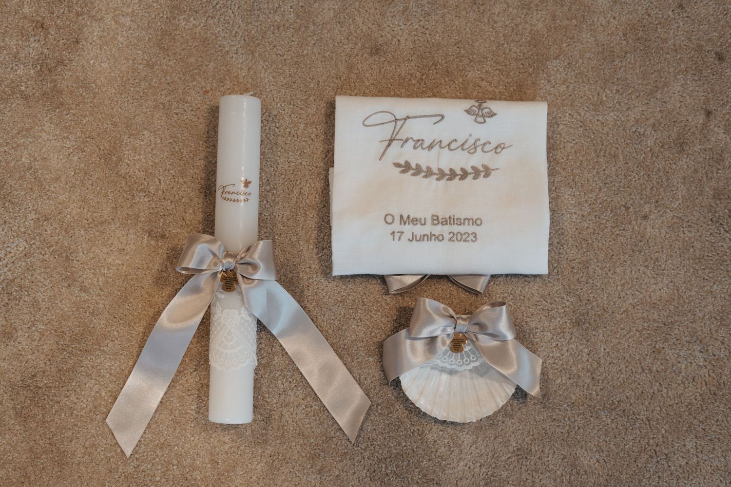 Wedding details including candle and name card arranged on beige surface.