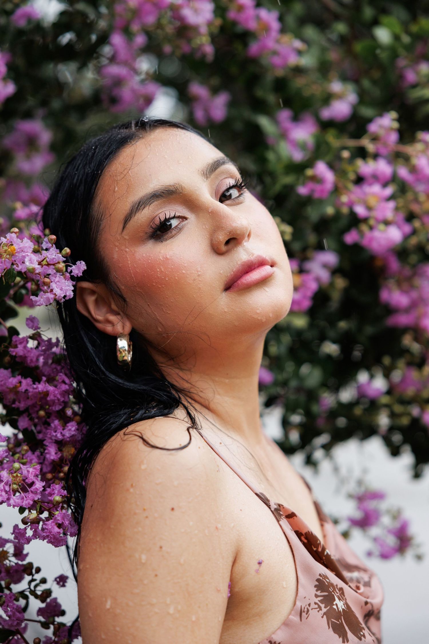 Artistic portrait amidst vibrant purple flowers and green foliage with soft natural lighting.