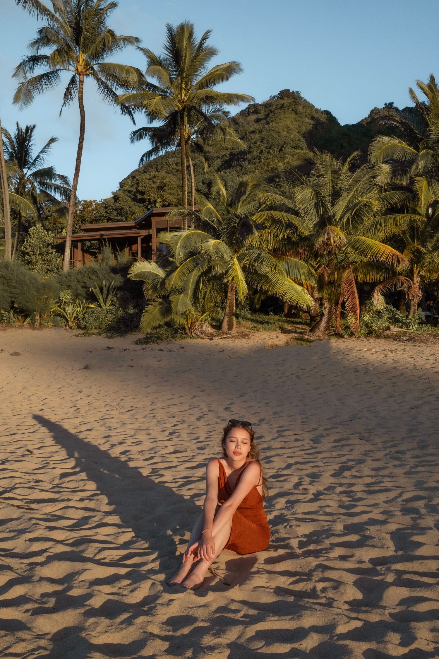 Sunset beach scene with palm trees and mountains in Hawaii.