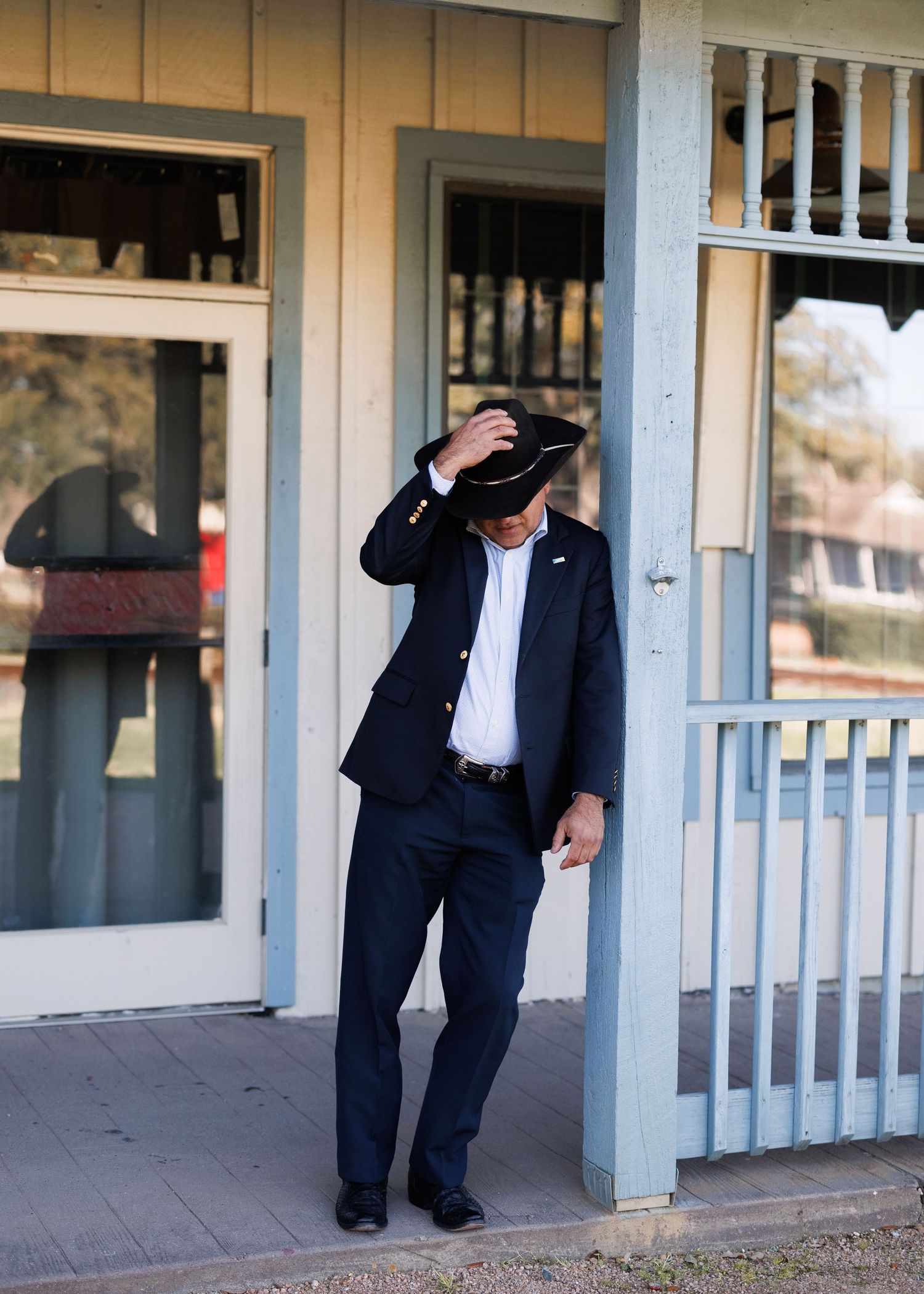 Collage of formal-attired person checking different entryways and door frames of a light blue building exterior.