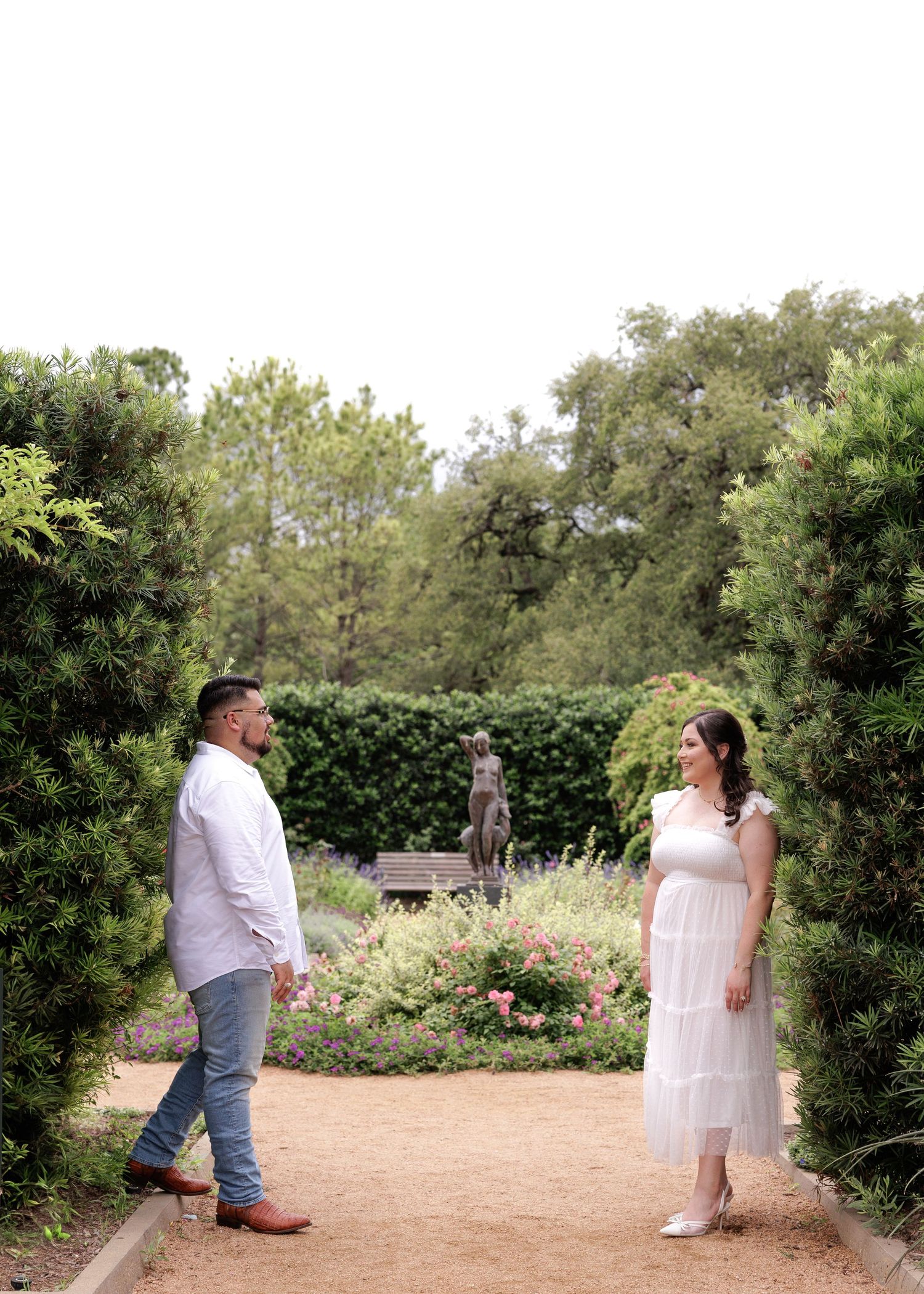 A sequence of shots showing two people in white clothing interacting in an outdoor garden setting with greenery.