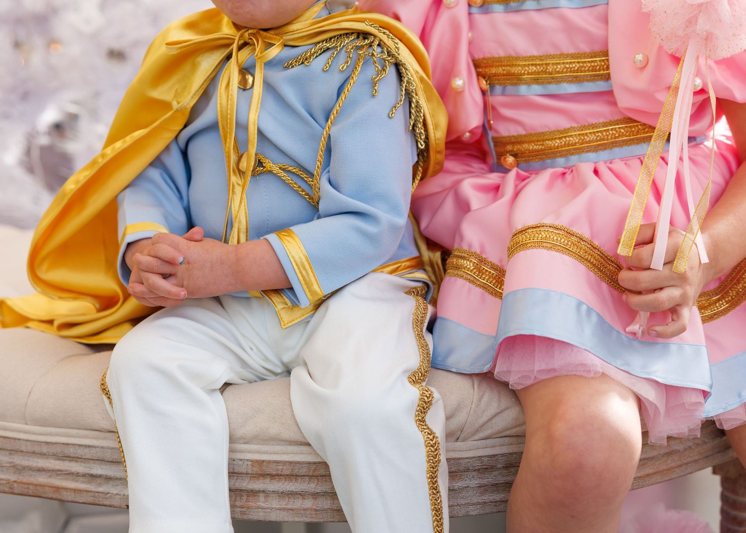 Two people in coordinating pink and blue outfits sit together on wooden steps holding hands.