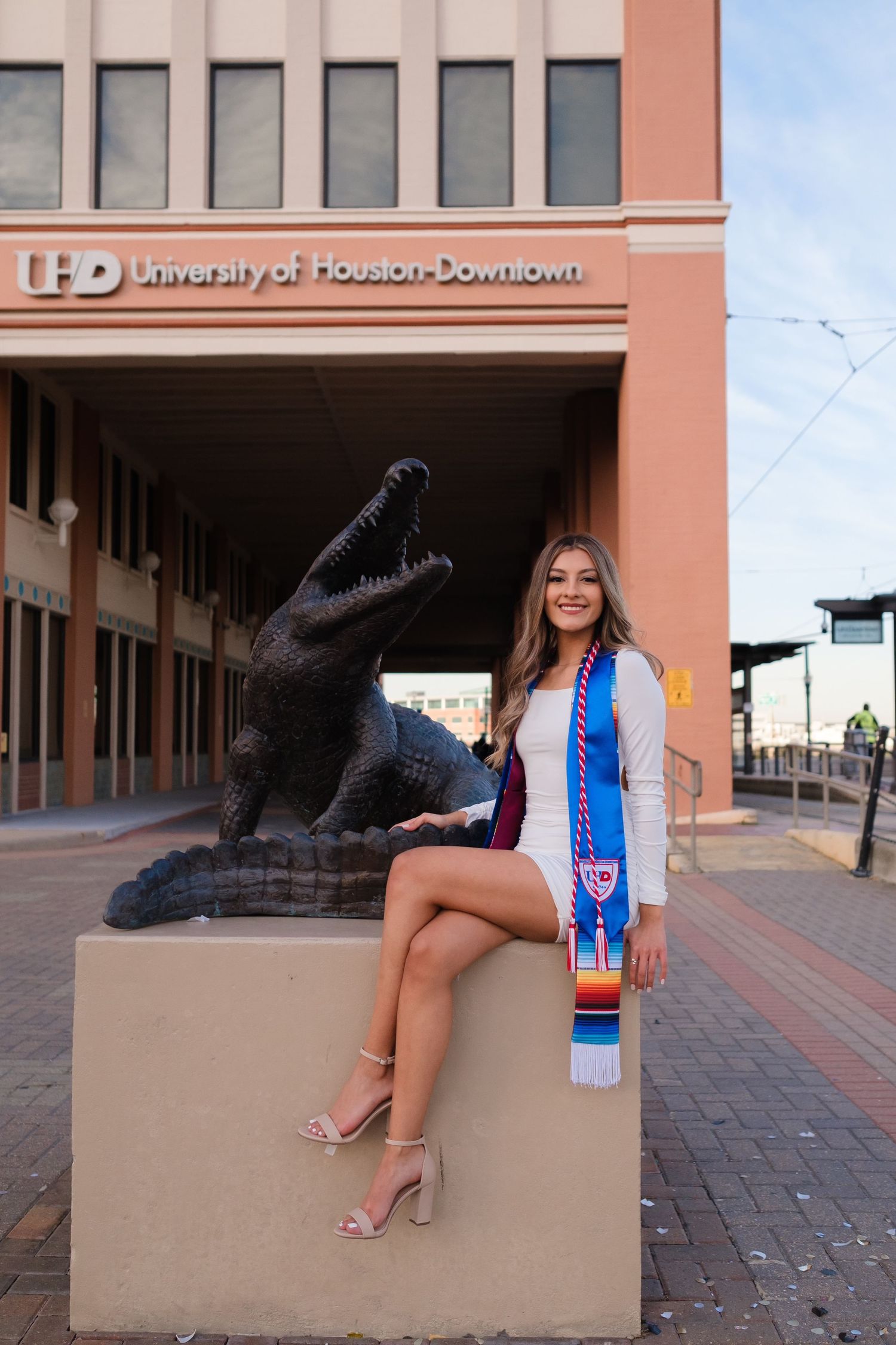 Graduation photo taken by UHD entrance with black cougar statue in downtown Houston campus setting.