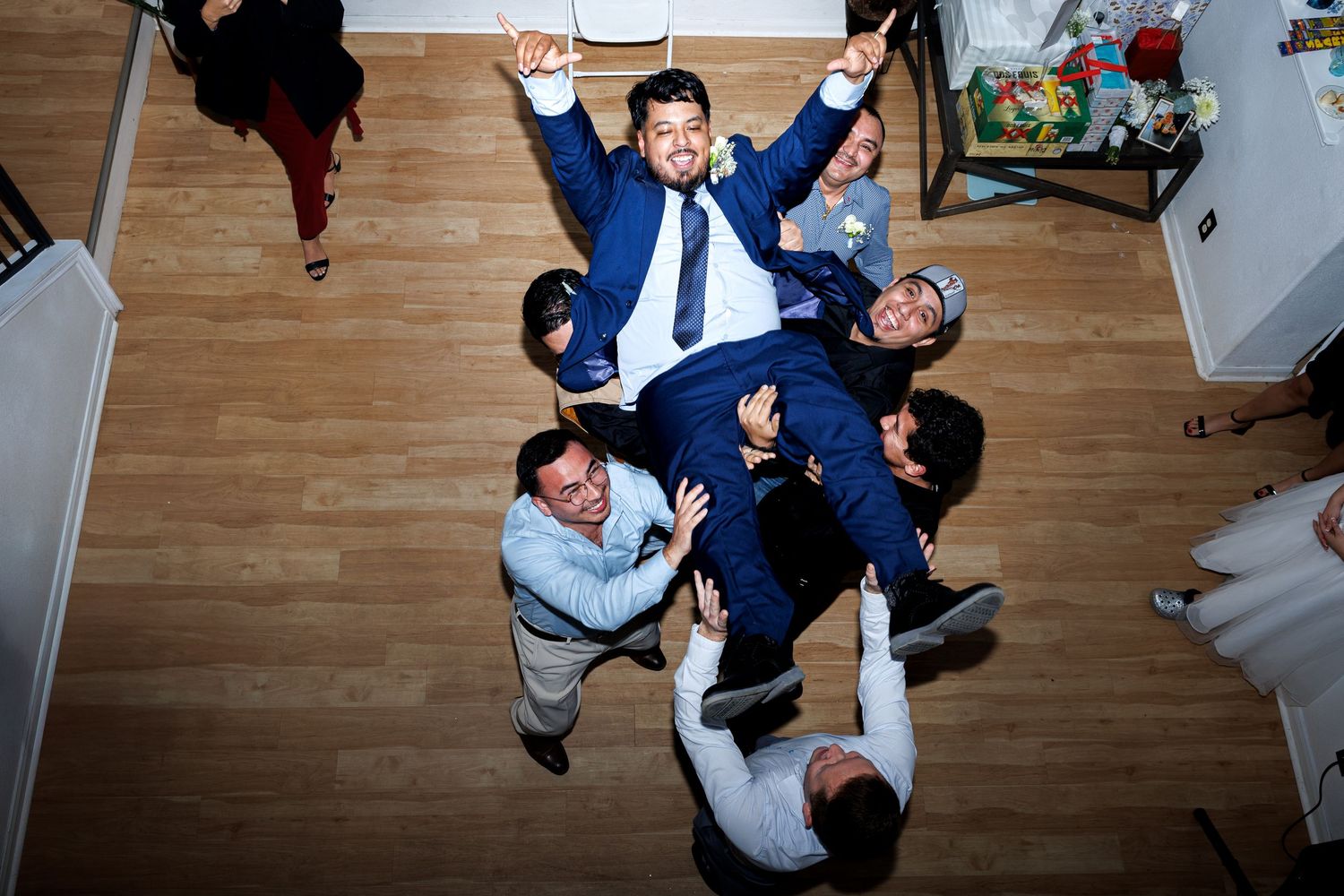 Overhead view of business people celebrating success in an office with hardwood floors and raised arms.