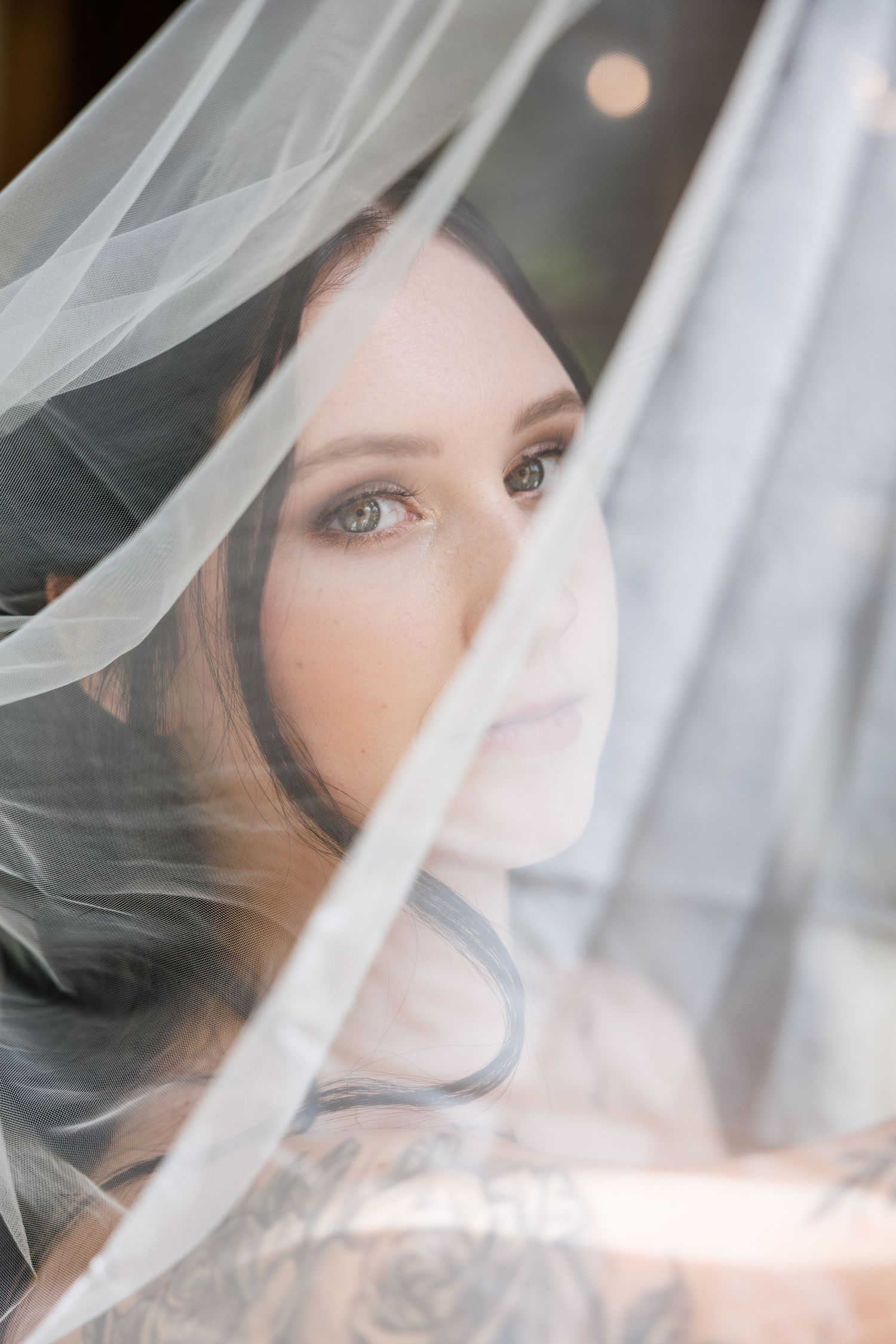 A dreamy bridal portrait through delicate white veil fabric creating an ethereal and romantic atmosphere.