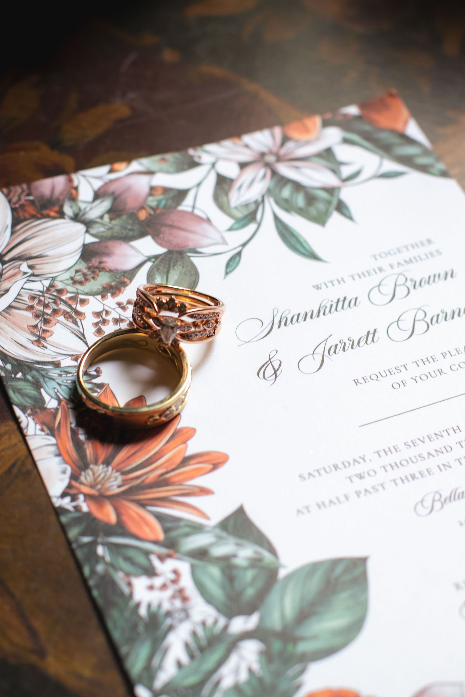 Wedding invitation with rose gold rings featuring floral design.