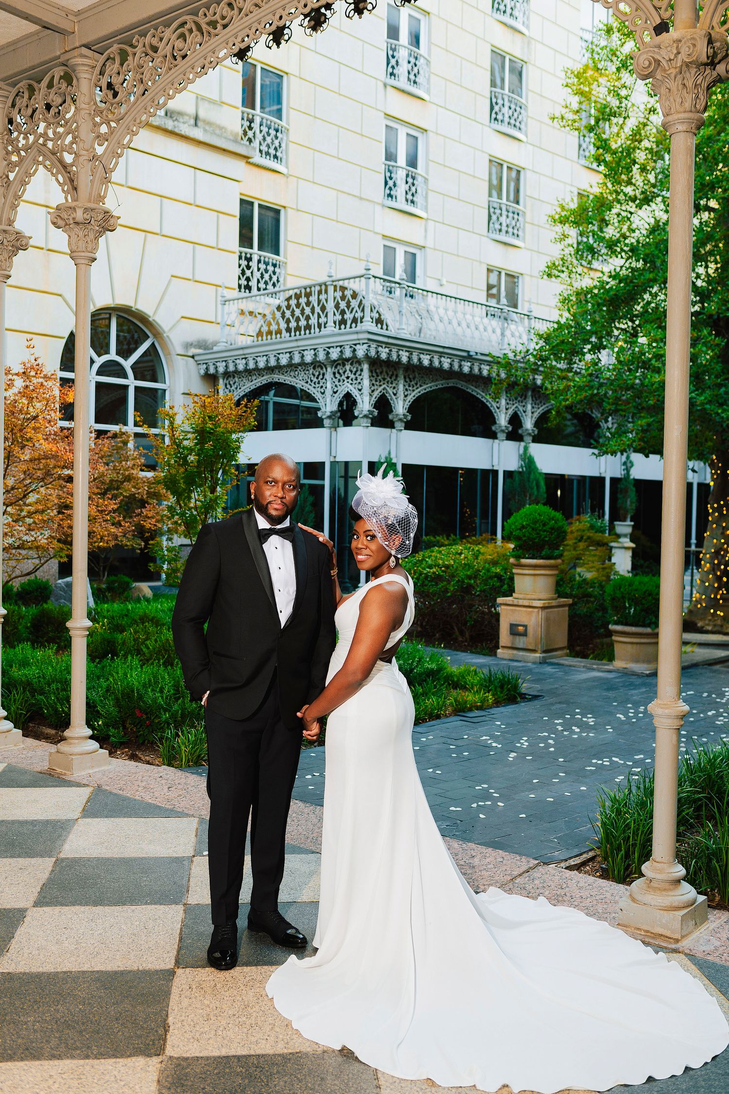 Elegant wedding photos captured at a historic venue with ornate white columns and archways in a garden courtyard setting. at Hotel Crescent