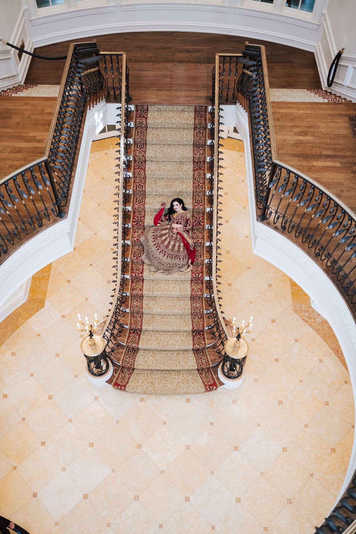 Overhead view of a grand staircase with a patterned carpet runner and white walls in a luxurious interior space. at the Olana wedding venue